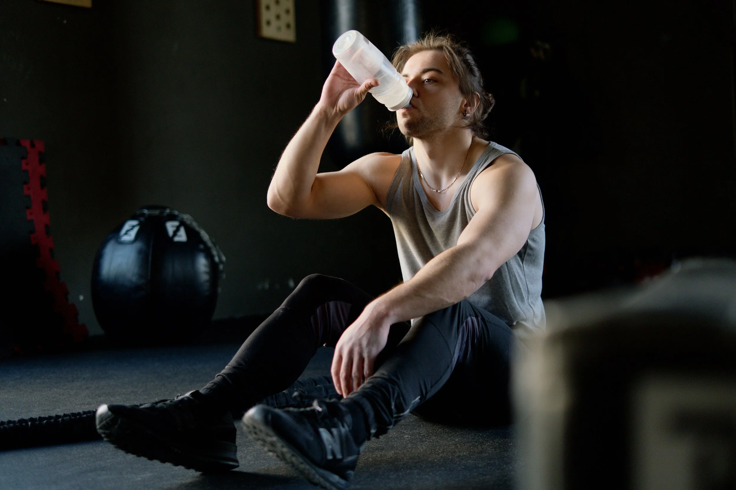 Man drinking water while recovering after a gym workout