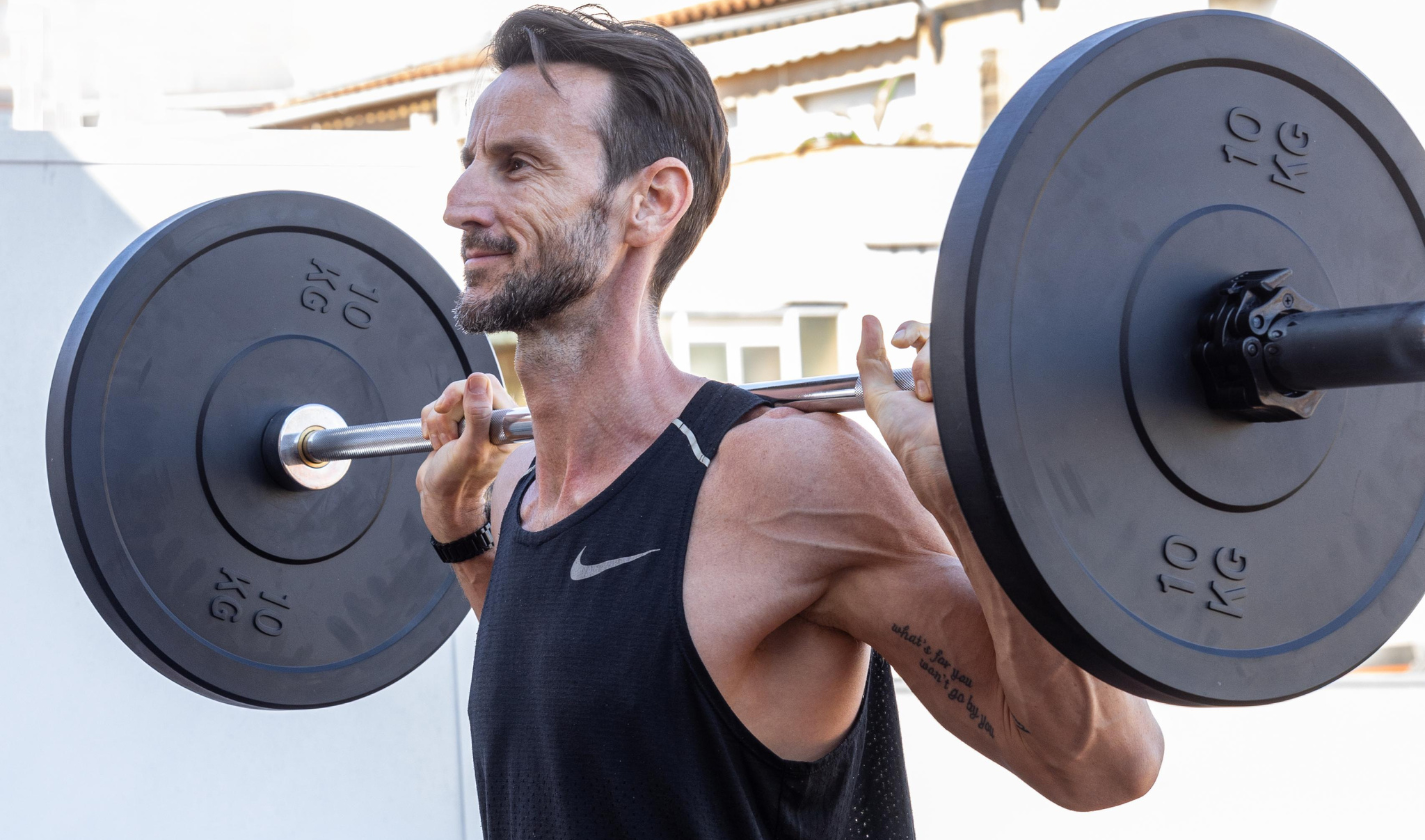 Male athlete demonstrating proper front squat form with controlled weight showing movement mastery before heavy loading