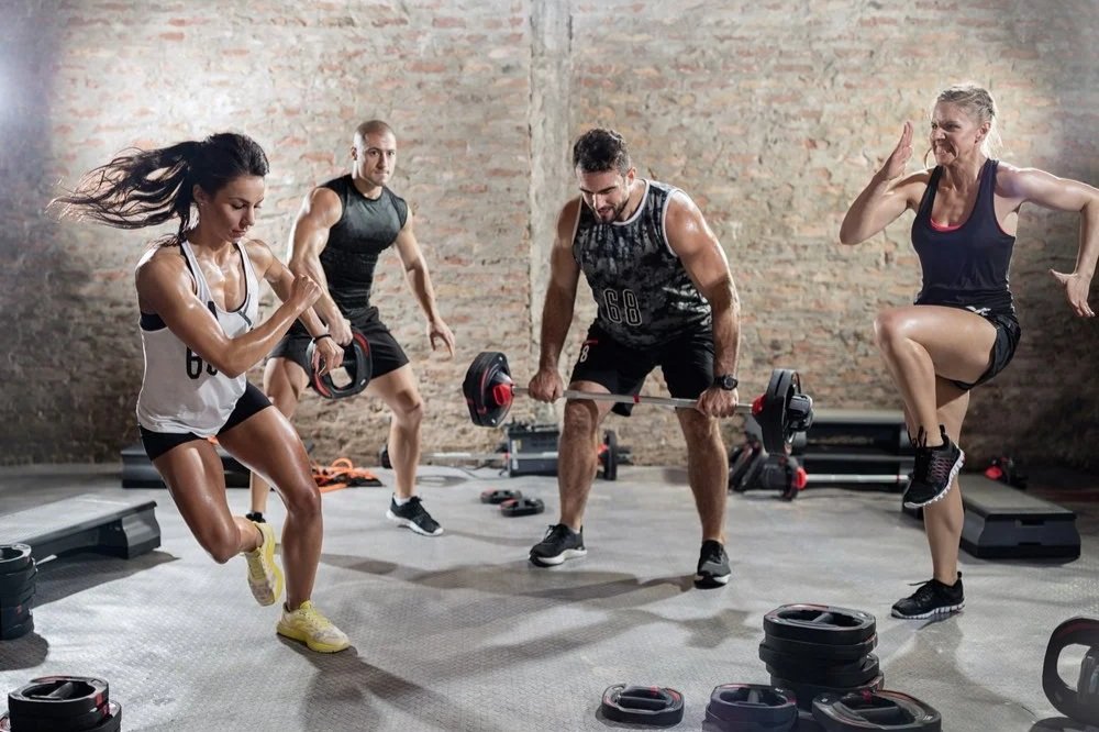 Four adults completing a high-intensity circuit training workout in a gym