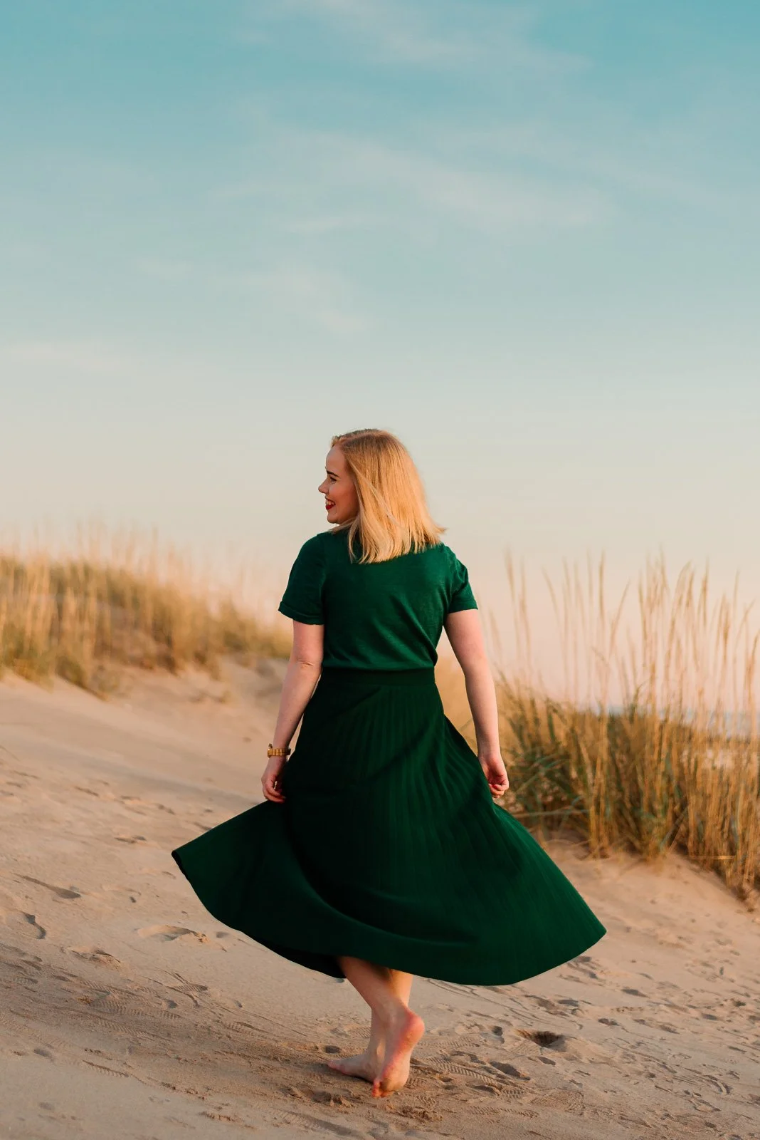 Tamperelainen valokuvaaja hiekkarannalla vihreässä mekossa.