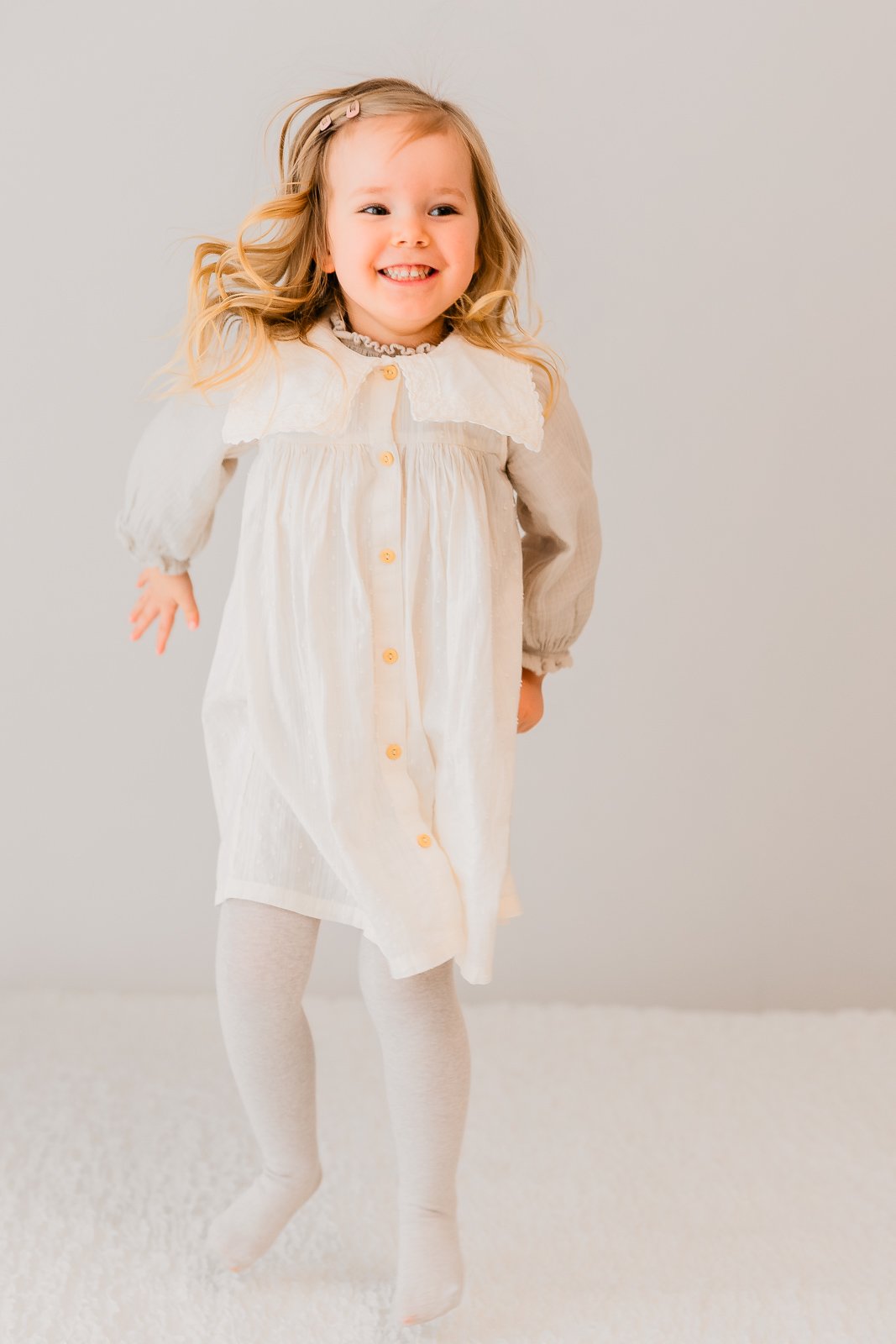 Lapsikuva studiolla Tampereella, tyttö hyppii sängyllä.