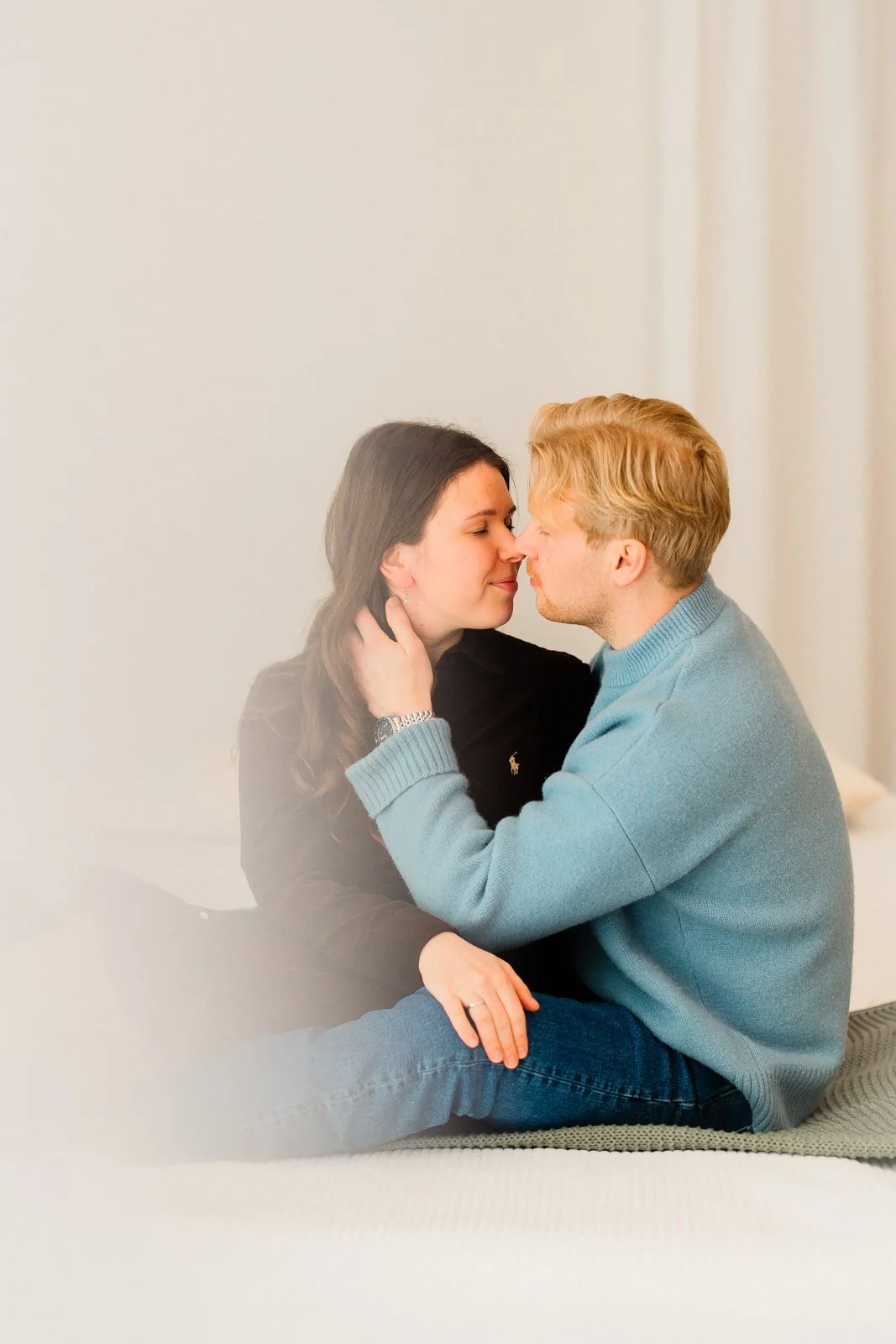 Parikuvaus studiossa Tampereella, pariskunta istuu sylikkäin sängyllä.