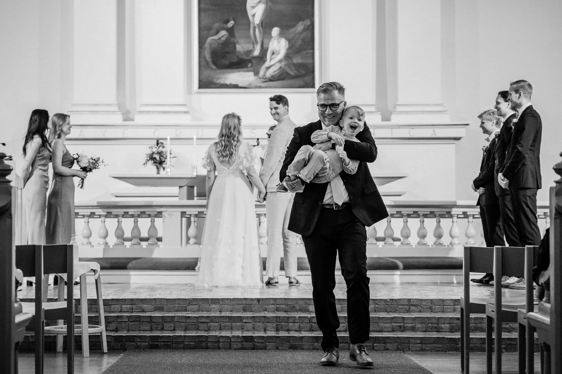 Dokumentaarinen hääkuvaus, hääparin lapsi isoisän sylissä vihkimisen aikana.