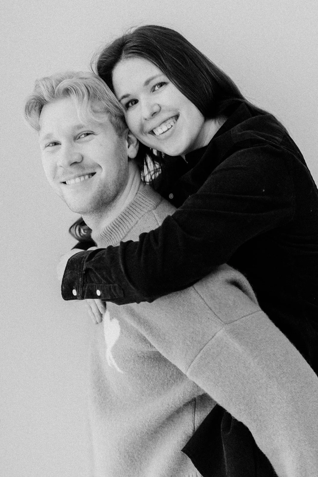 Parikuvaus studiolla Tampereella, pariskunta katsoo kameraan ja nainen on reppuselässä.