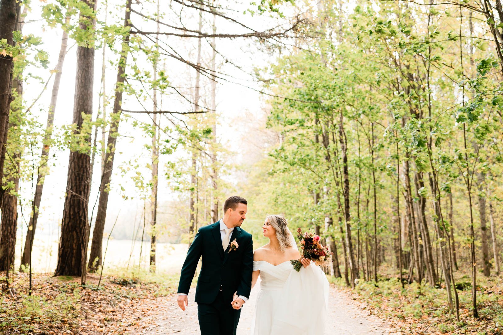 Hääkuvaus Lahti, hääpari kävelemässä kohti kameraa vihreässä maisemassa.