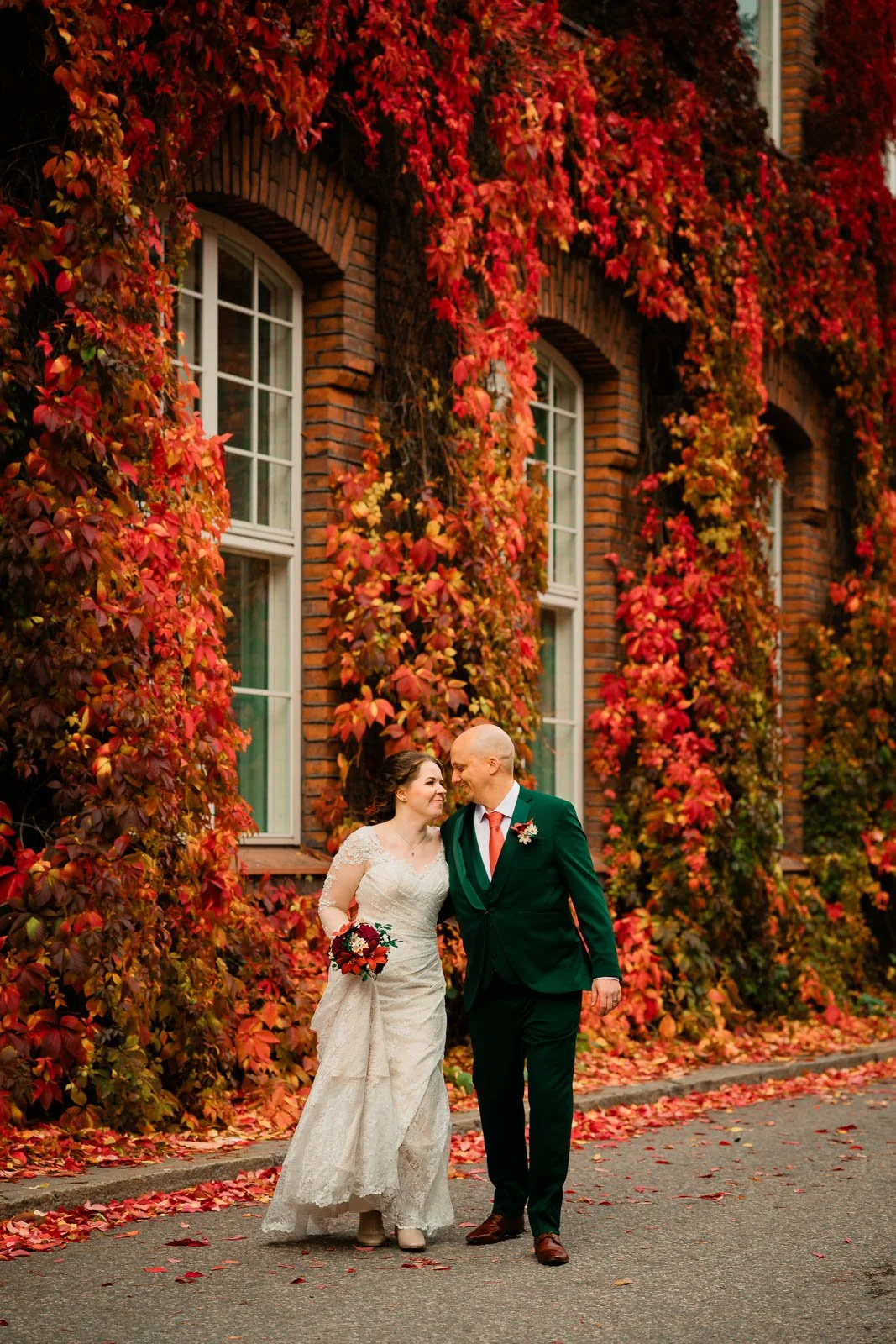Häävalokuvaaja Tampere, hääpari kävelemässä kohti kameraa, taustalla upea punainen seinä.