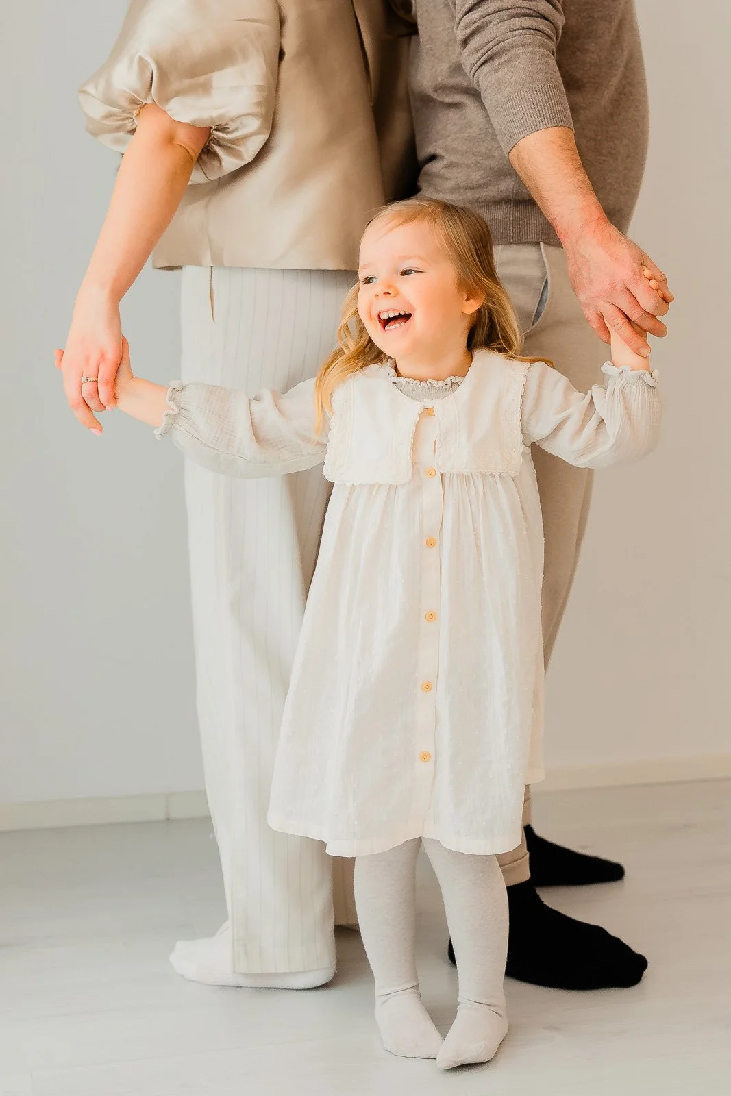 Perhekuvaus studiolla Tampereella, lapsi pyörii käsi kädessä piirissä äidin ja isän kanssa.