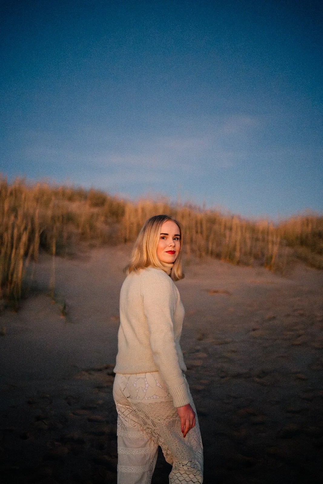 Valokuvaaja Lahdesta katsoo kameraan hiekkarannalla.