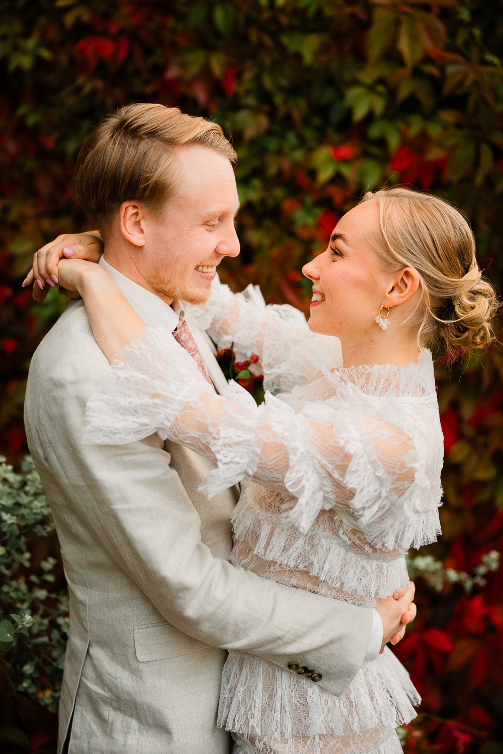 Hääkuvaus Tampereella Ravintola Pihassa, hääpari punaista ruskaseinää vasten.