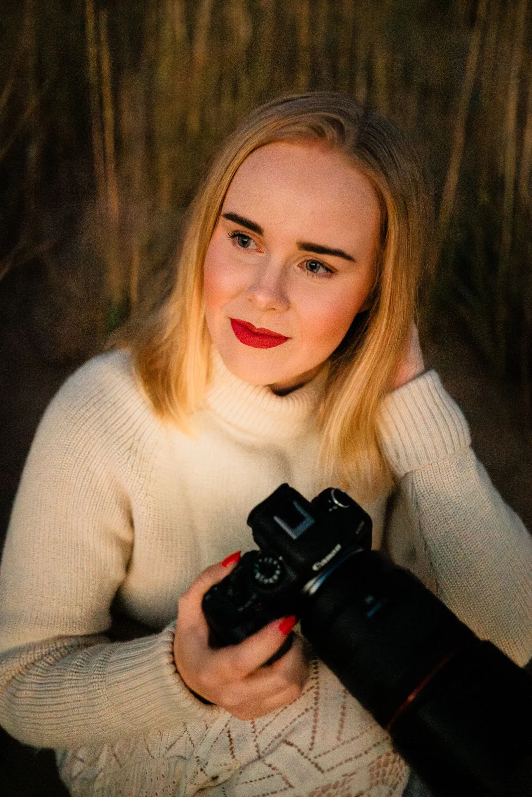 Valokuvaaja Lea Tampereelta istuu hiekkarannalla kamera kädessä.