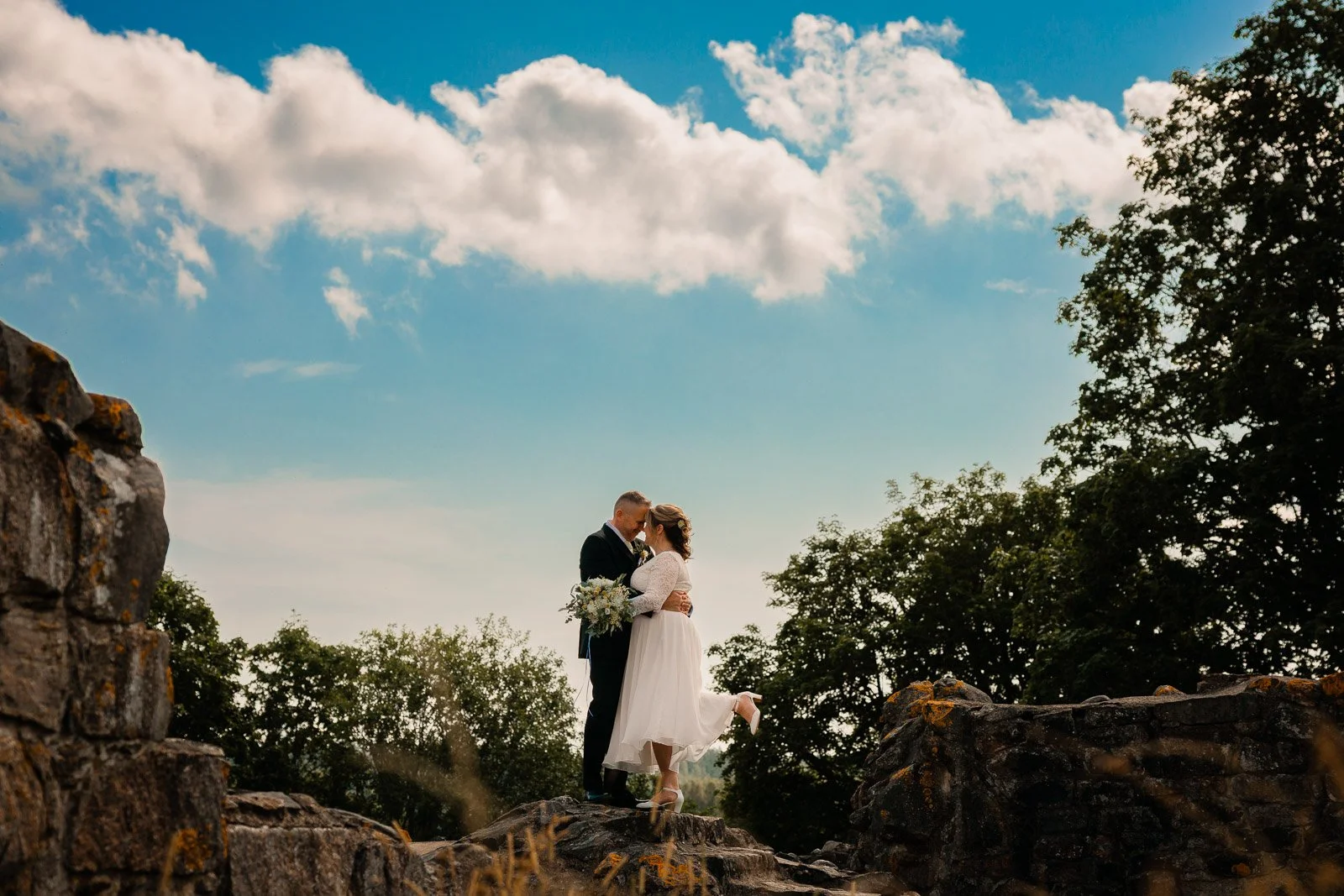 Hääkuva Kuusiston Linnaraunioilla, hääparin taustalla sininen taivais.