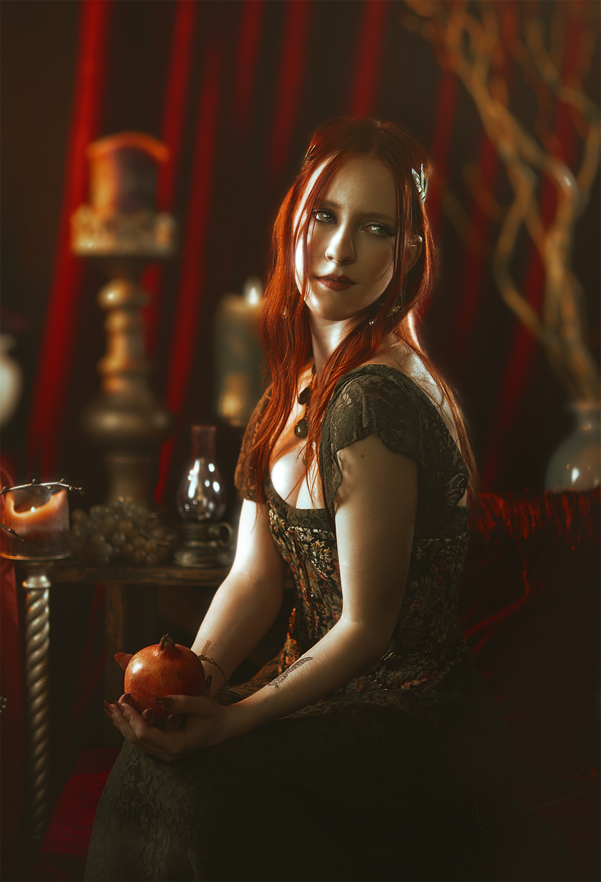 Persephone inspired dark goddess cosplay portrait with pomegranate, red velvet and candlelight. Fine art fantasy photography based on Greek mythology, featuring rich colors and a moody, storytelling atmosphere.