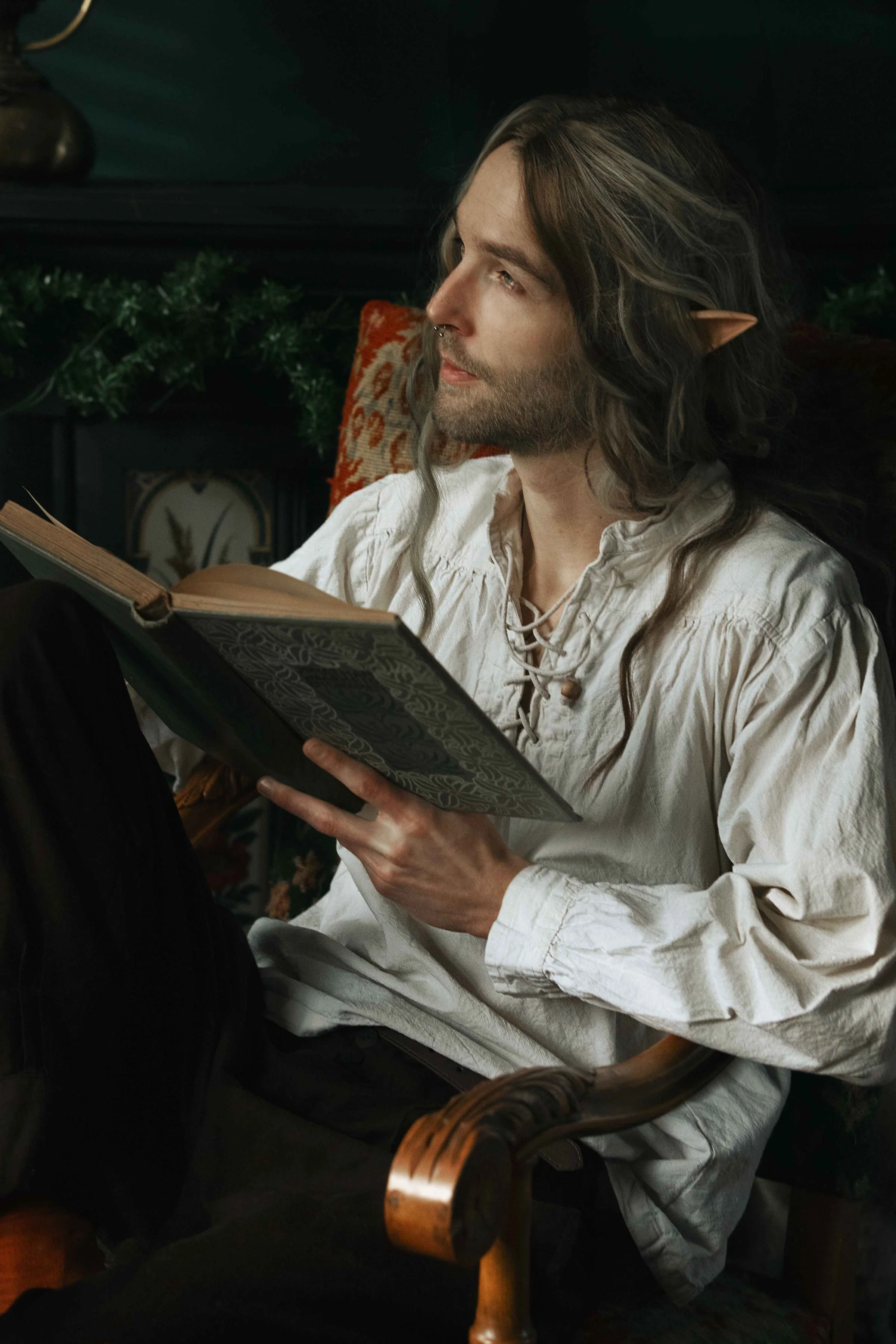 Dreamy fine art portrait of Rico as a scholar reading by candlelight. Painterly fantasy photography inspired by folklore and classical paintings, featuring books, glass bottles and warm light. Moody, romantic storytelling imagery in a fine art studio