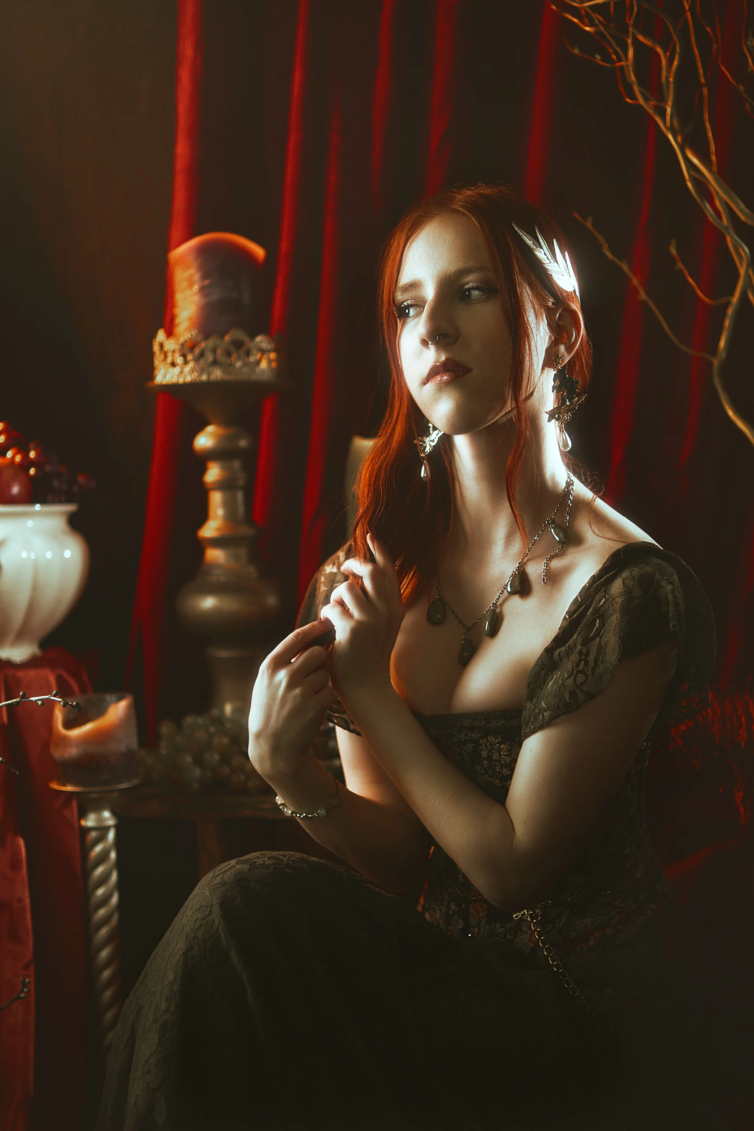 Persephone inspired dark goddess cosplay portrait with pomegranate, red velvet and candlelight. Fine art fantasy photography based on Greek mythology, featuring rich colors and a moody, storytelling atmosphere.