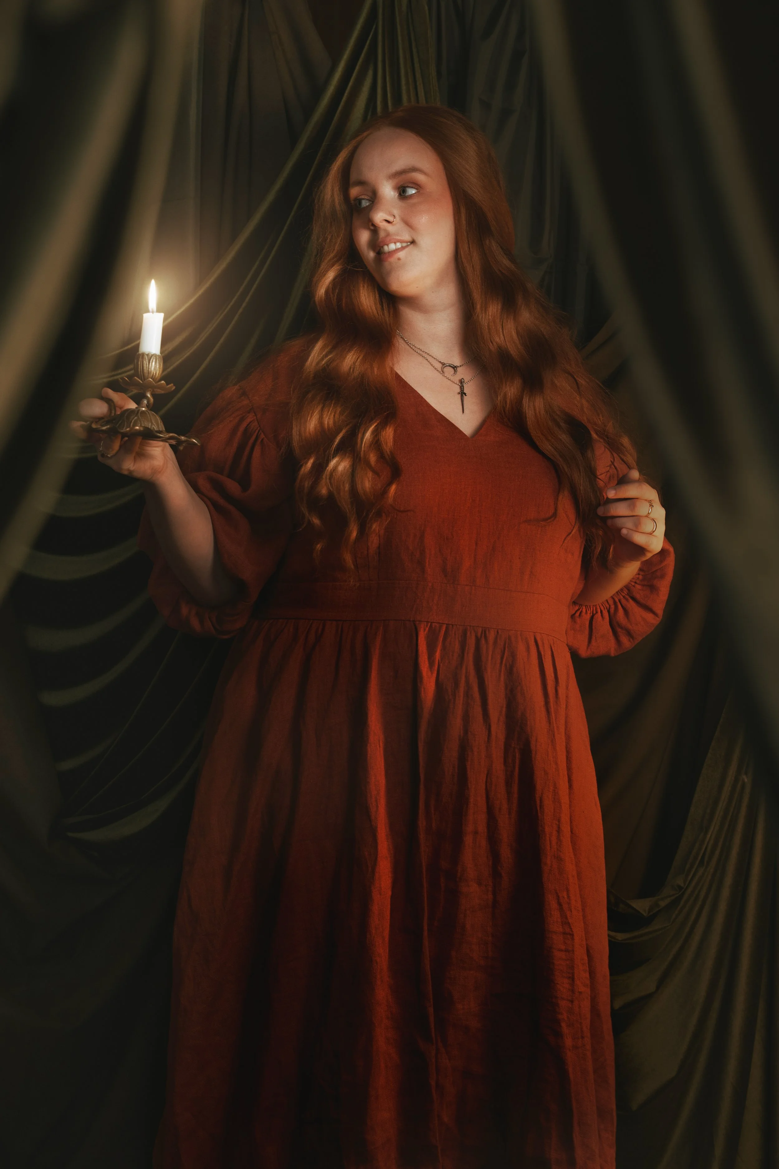 Dark romantic fine art portrait of a woman in deep red and violet tones with candlelight and vintage styling. Painterly fantasy photography inspired by baroque art and historical fashion, featuring rich fabrics and soft dramatic light.