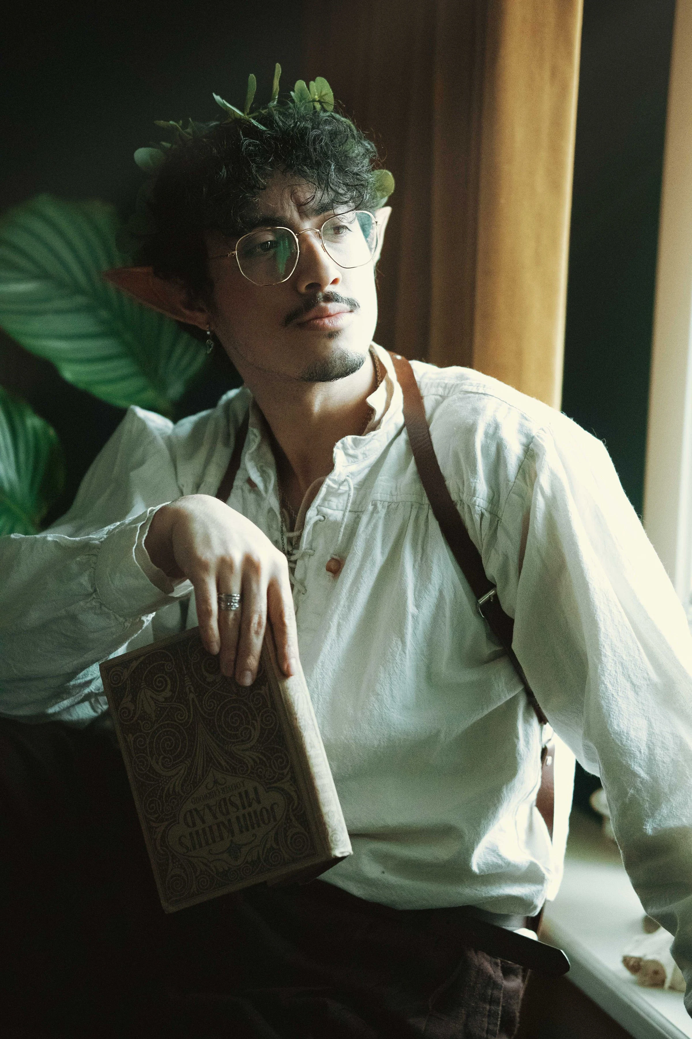 Person with elf-like features holding a decorative book.