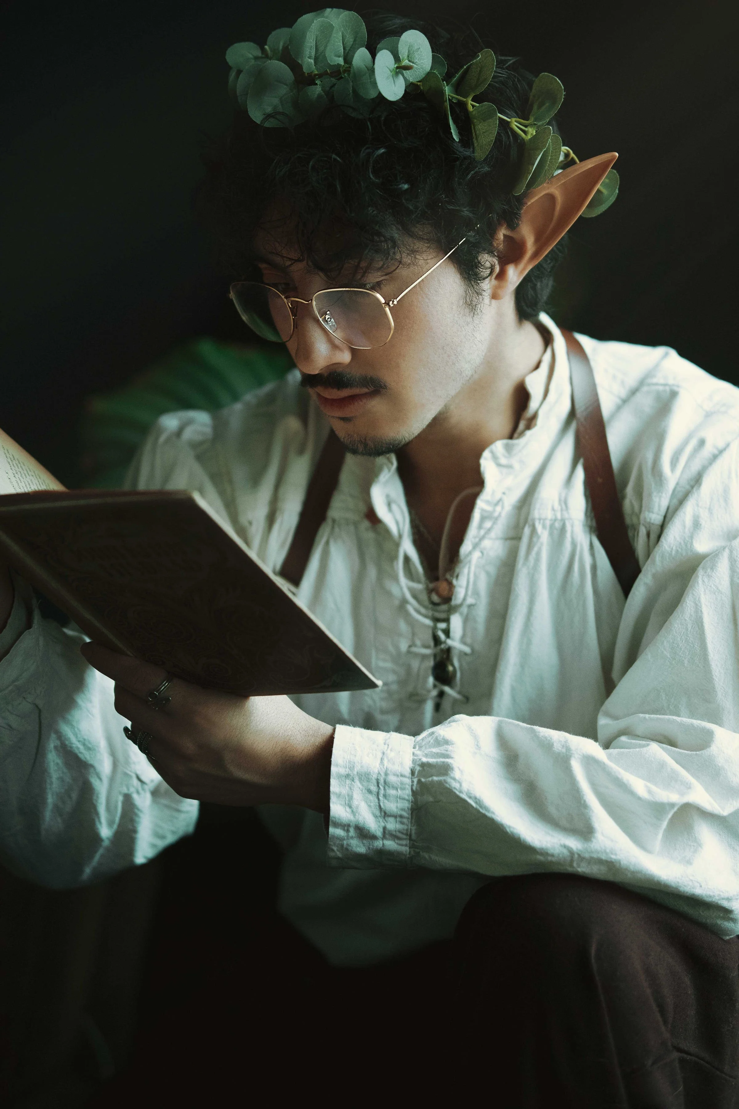 Dreamy fine art portrait of Dewa as a folkloric alchemist, surrounded by glass bottles, herbs and candlelight. Painterly fantasy photography inspired by historical apothecaries and storytelling portraiture. Studio shoot in the Netherlands.