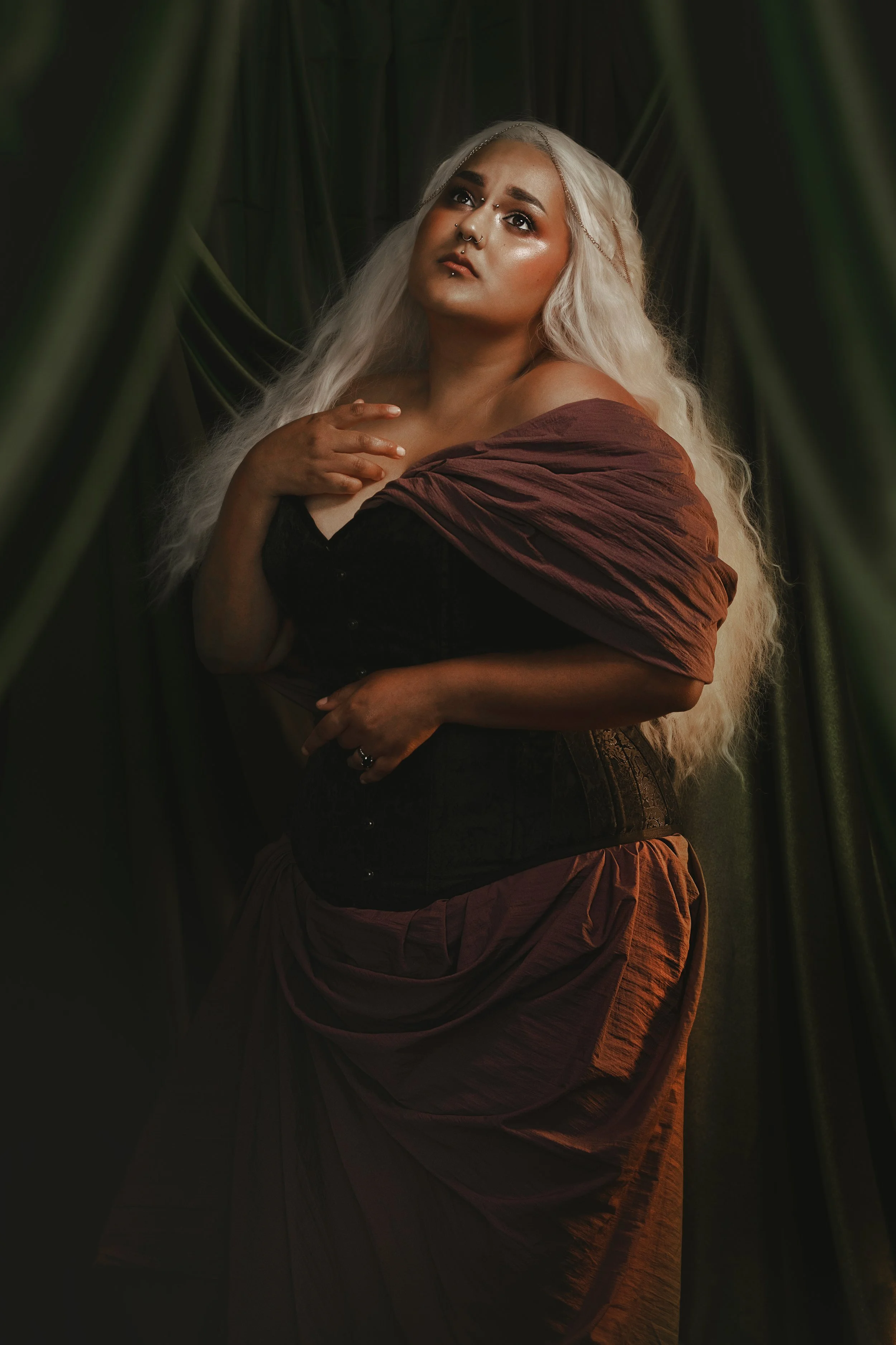 Dark romantic fine art portrait of a woman in deep red and violet tones with candlelight and vintage styling. Painterly fantasy photography inspired by baroque art and historical fashion, featuring rich fabrics and soft dramatic light.
