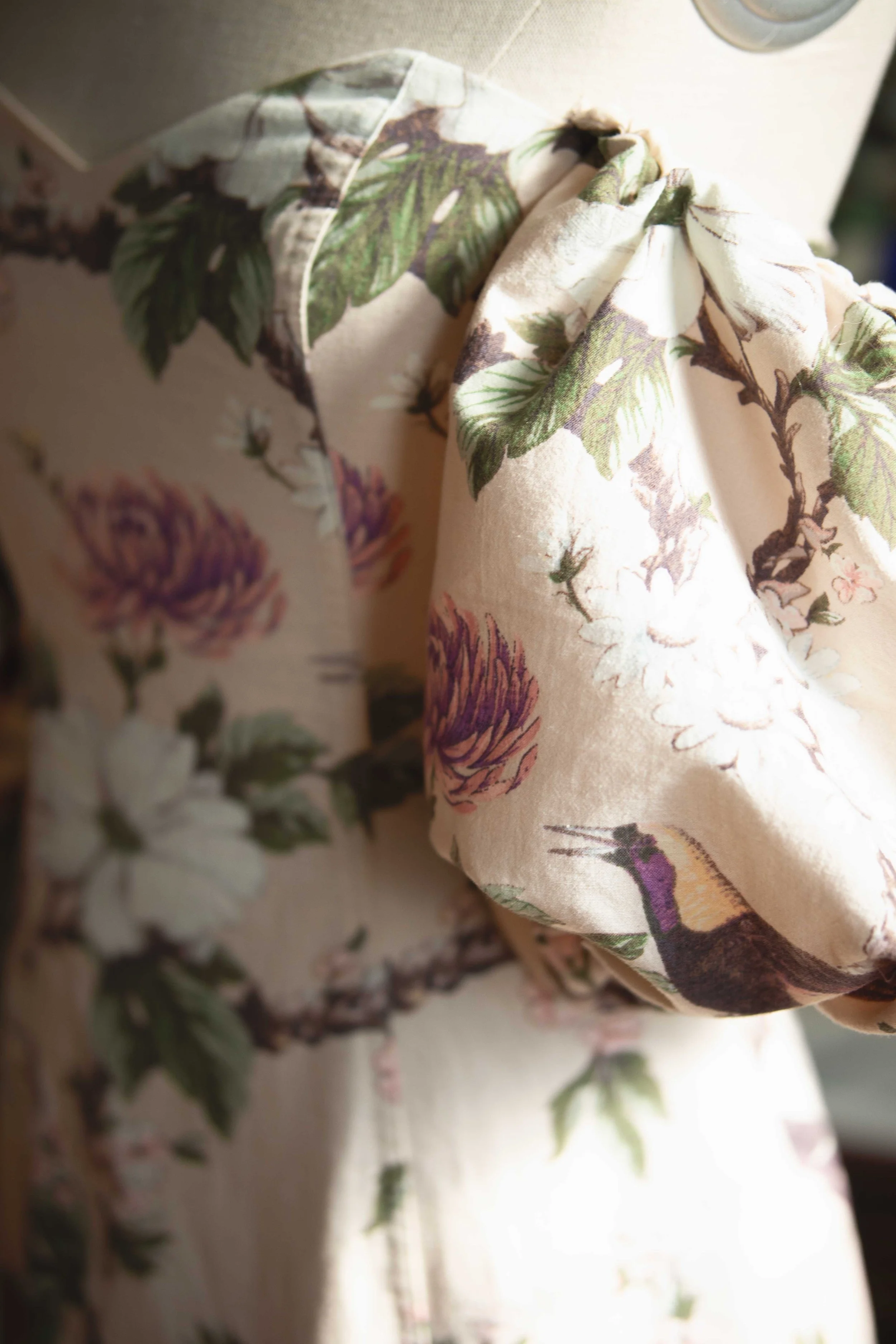 Close-up of floral-patterned dress with puff sleeves on a mannequin.