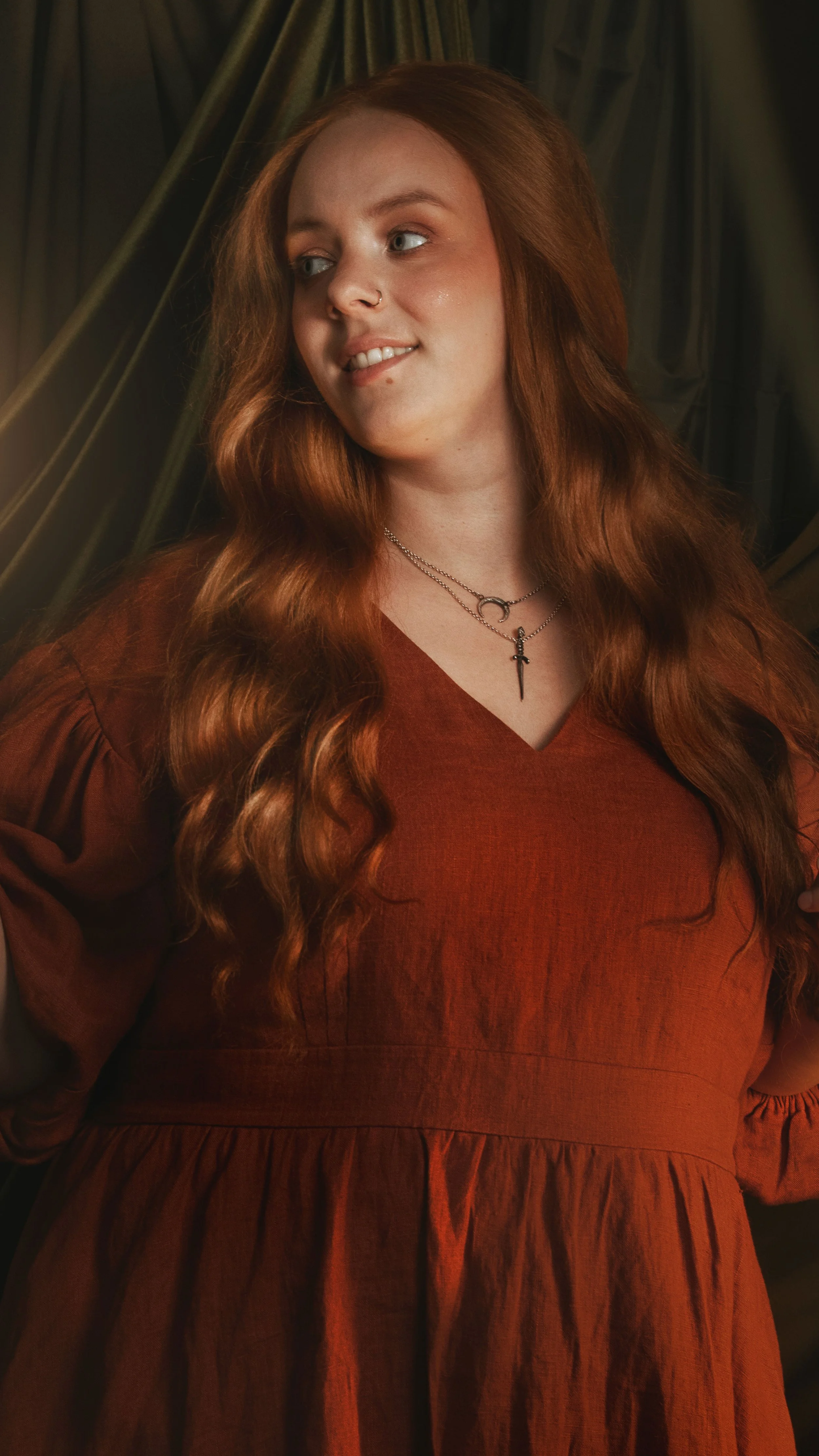 Dark romantic fine art portrait of a woman in deep red and violet tones with candlelight and vintage styling. Painterly fantasy photography inspired by baroque art and historical fashion, featuring rich fabrics and soft dramatic light.