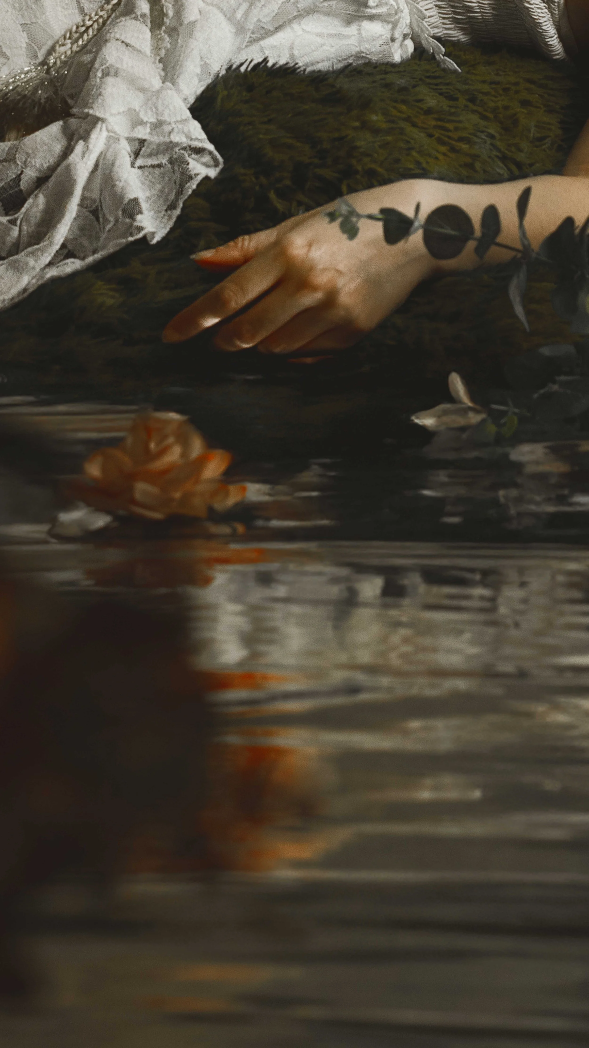 Dreamy fine art portrait of a woman in water surrounded by flowers and soft reflections. Painterly fantasy photography inspired by folklore, mythology and classical paintings. Romantic, ethereal imagery with storytelling atmosphere and natural elemen