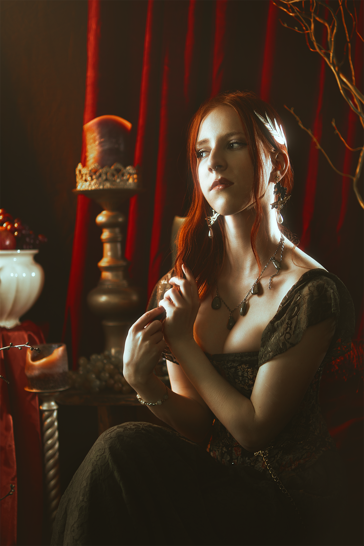 Persephone inspired dark goddess cosplay portrait with pomegranate, red velvet and candlelight. Fine art fantasy photography based on Greek mythology, featuring rich colors and a moody, storytelling atmosphere.