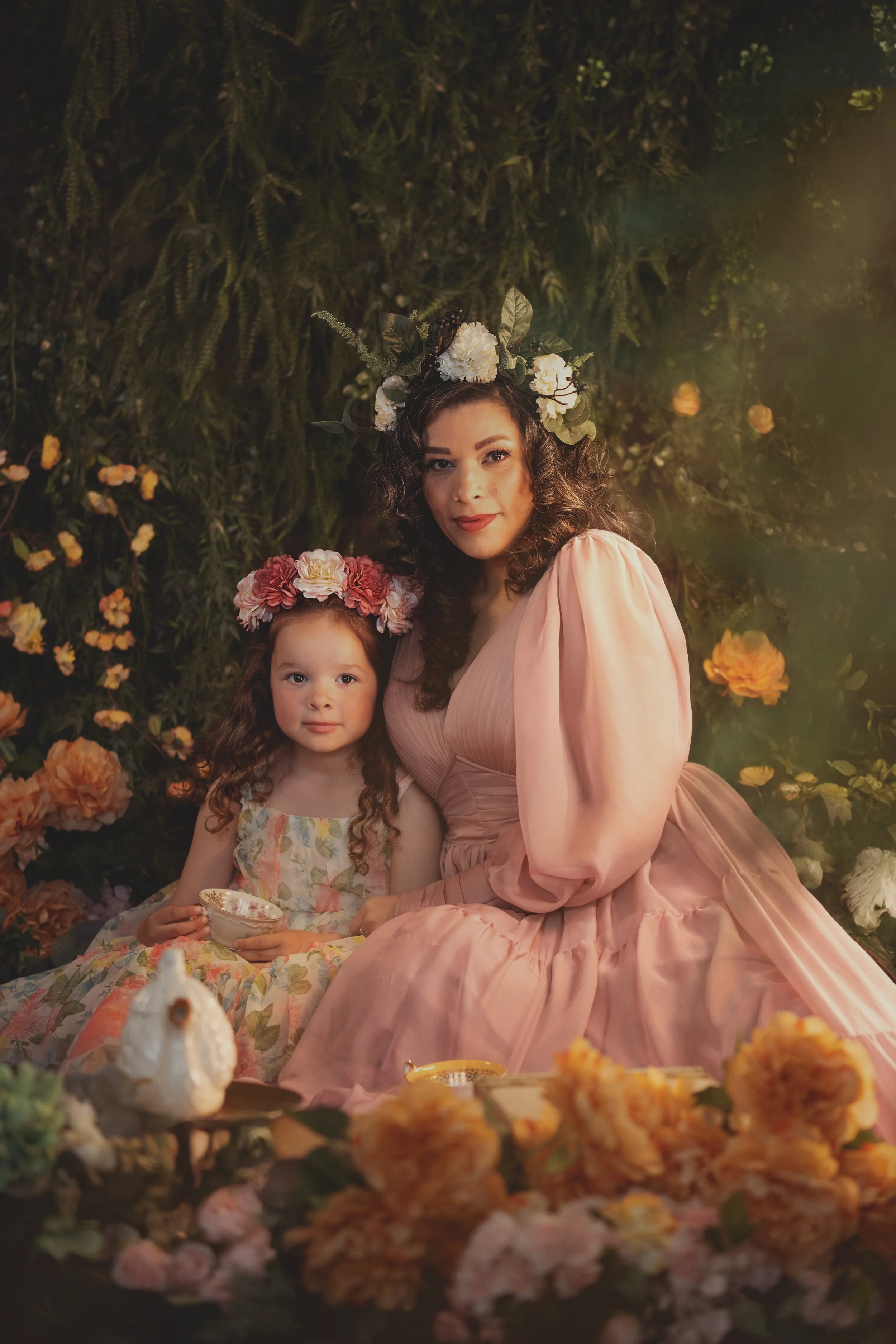Dreamy mommy and me fine art portrait of a mother and child surrounded by flowers and soft golden light. Painterly photography inspired by fairytales and nature, capturing tenderness, connection and a warm storytelling atmosphere.