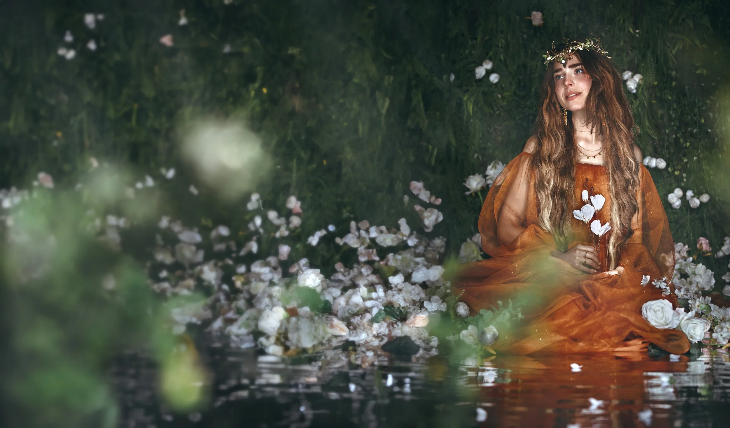 Dreamy fine art portrait of a flower nymph in water surrounded by blossoms and greenery. Ethereal fantasy photography inspired by folklore, mythology and nature. Painterly, romantic imagery with soft light, floral details and storytelling atmosphere.