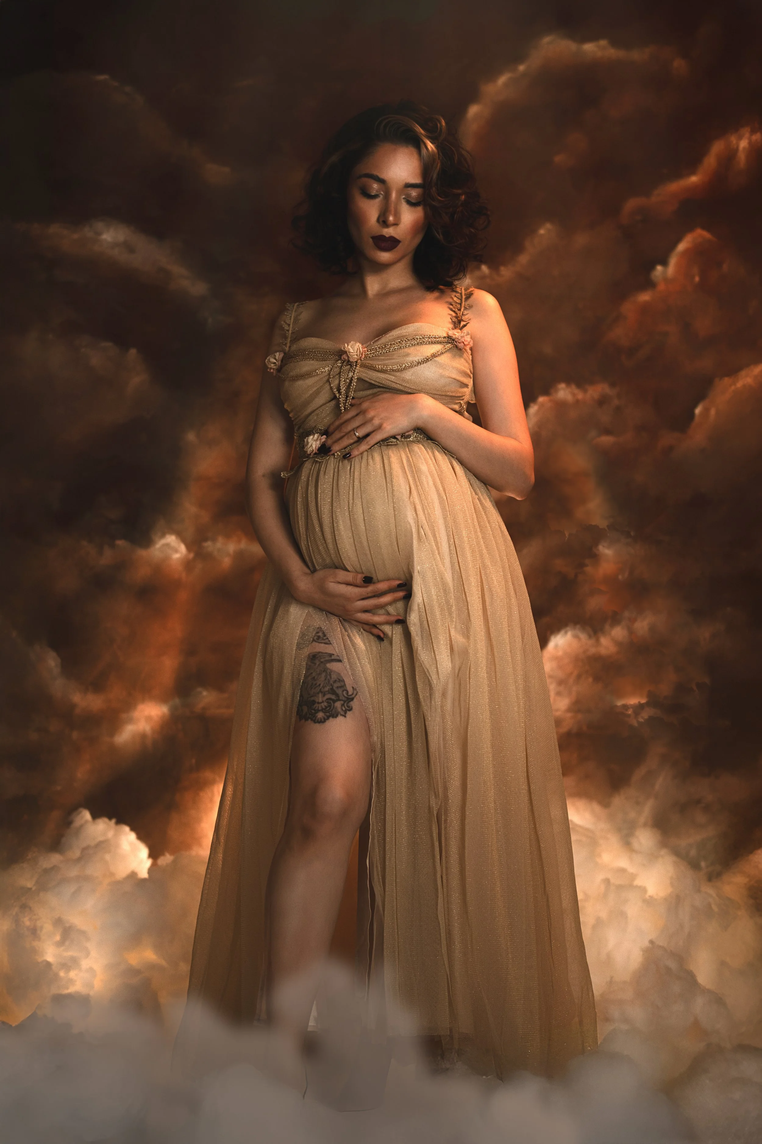 Dreamy fine art maternity portrait of a pregnant woman surrounded by clouds and soft golden light. Ethereal pregnancy photography inspired by classical paintings, divine femininity and mythology. Romantic, painterly motherhood imagery with flowing fa