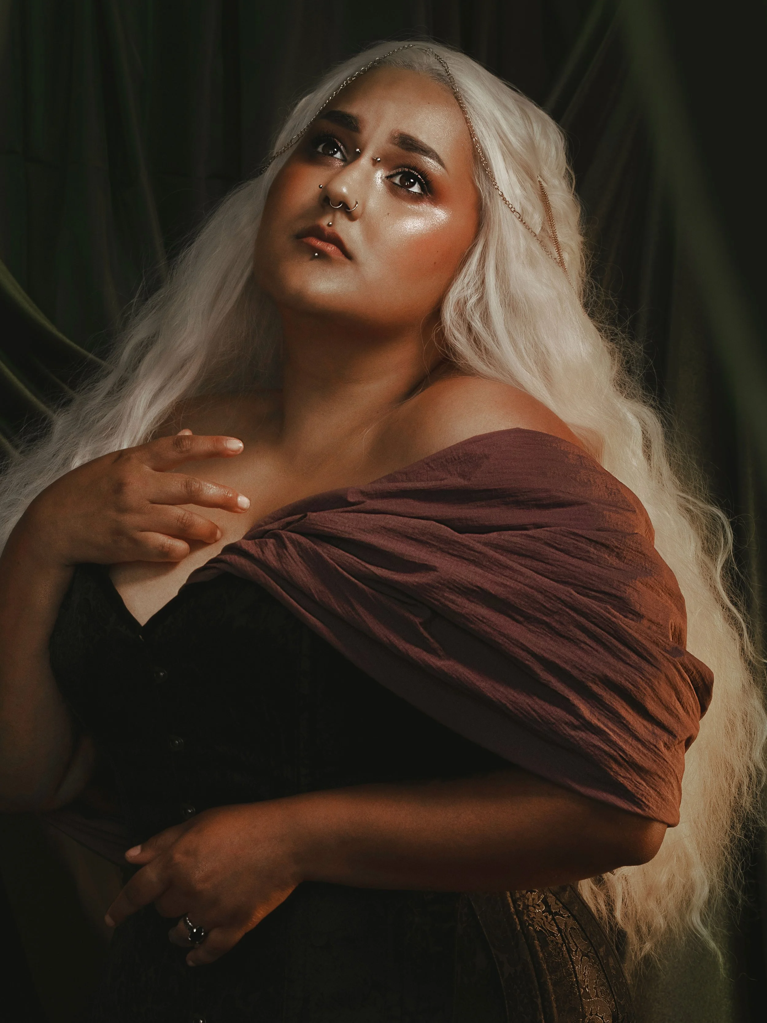 Dark romantic fine art portrait of a woman in deep red and violet tones with candlelight and vintage styling. Painterly fantasy photography inspired by baroque art and historical fashion, featuring rich fabrics and soft dramatic light.