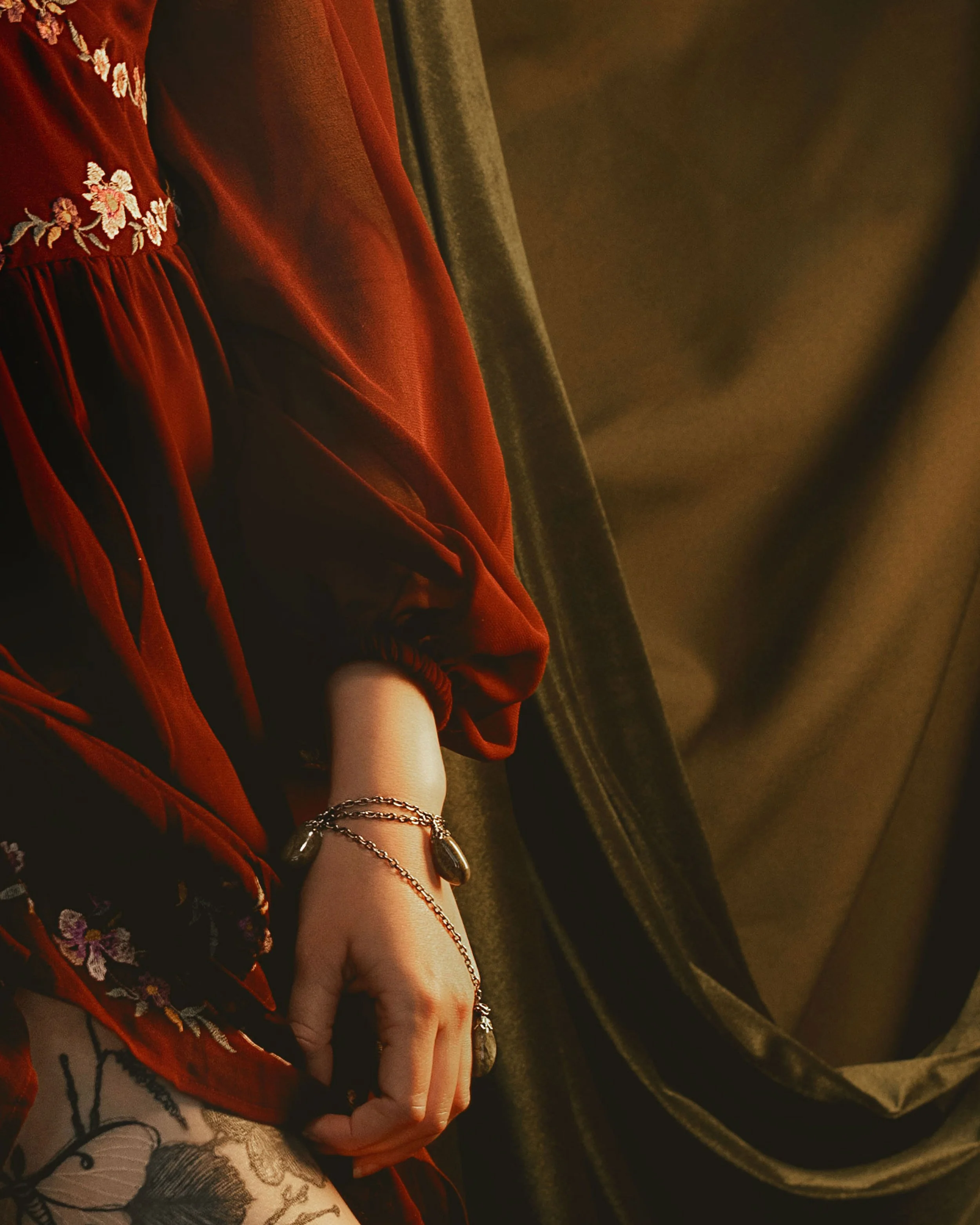 Dark romantic fine art portrait of a woman in deep red and violet tones with candlelight and vintage styling. Painterly fantasy photography inspired by baroque art and historical fashion, featuring rich fabrics and soft dramatic light.