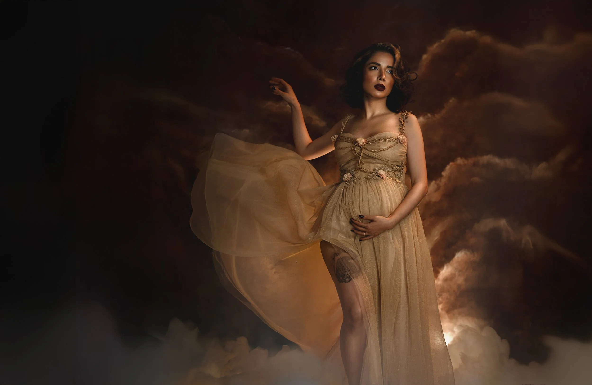 Dreamy fine art maternity portrait of a pregnant woman surrounded by clouds and soft golden light. Ethereal pregnancy photography inspired by classical paintings, divine femininity and mythology. Romantic, painterly motherhood imagery with flowing fa