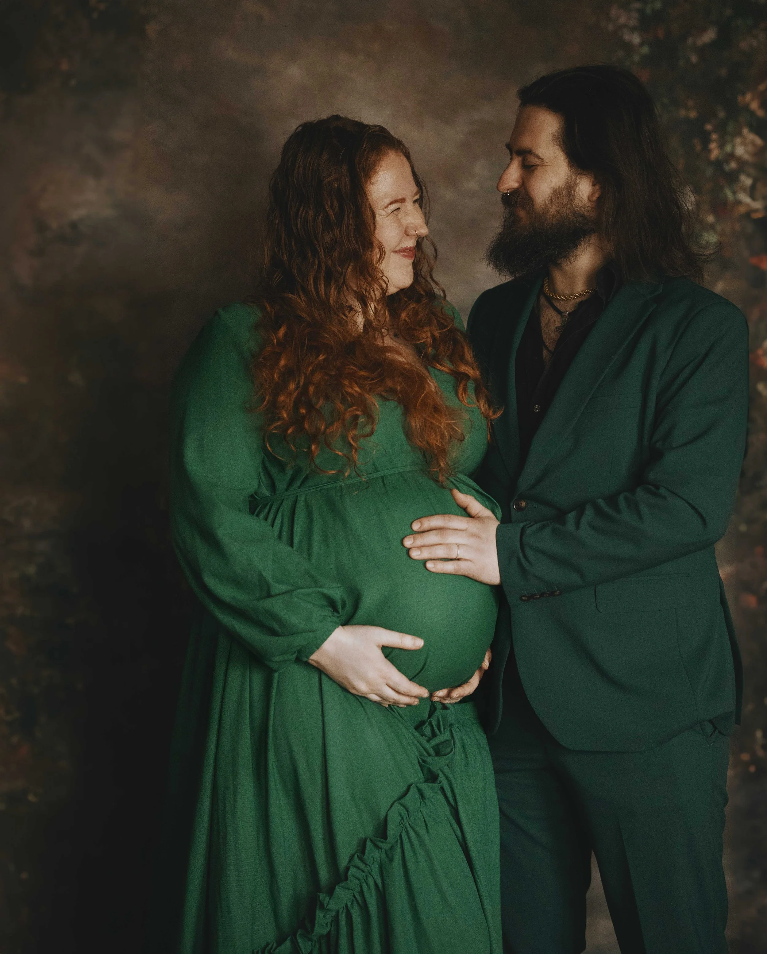 Pregnant woman in green dress with partner in green suit