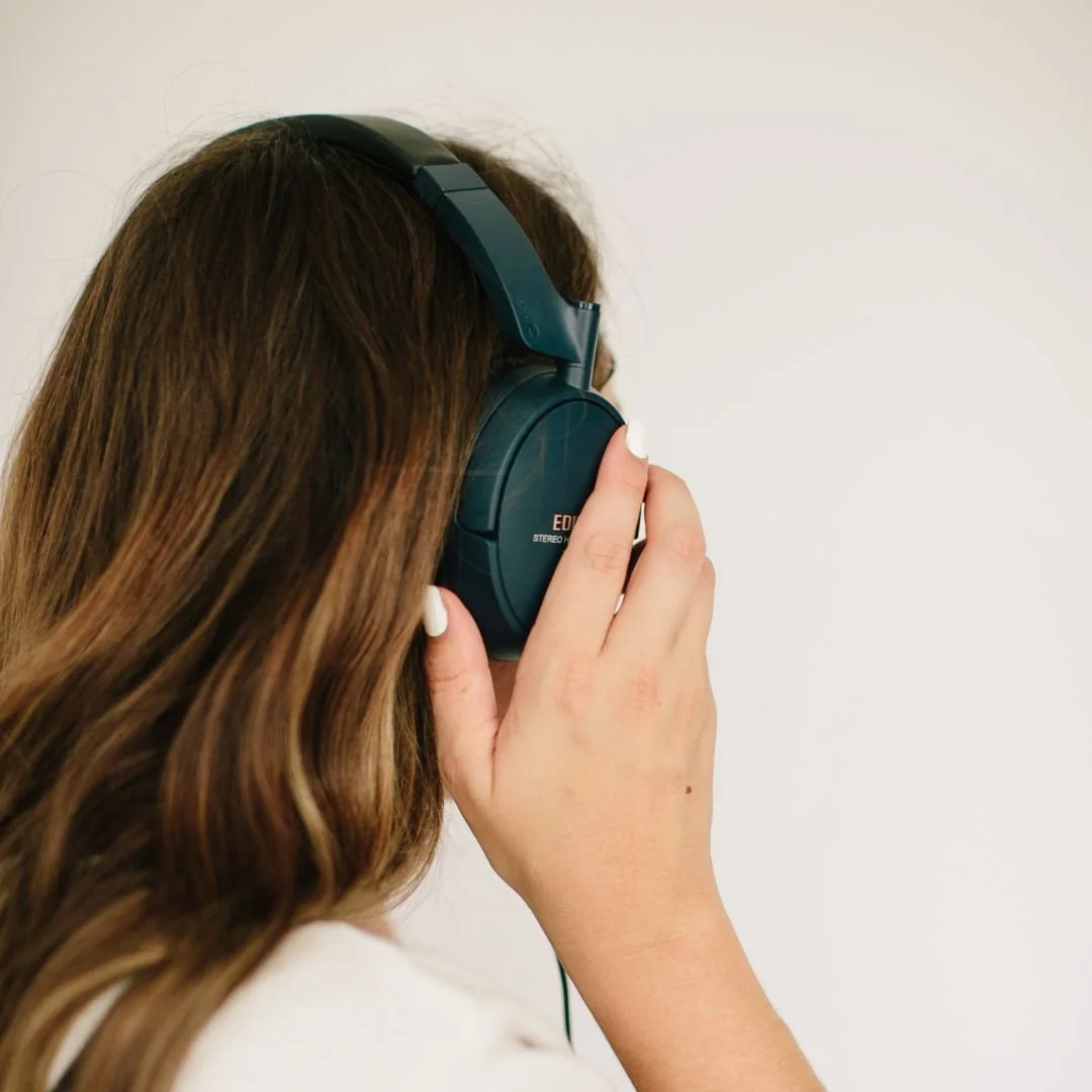 Podcast host Sandra wearing pink blazer while sitting in front of microphone