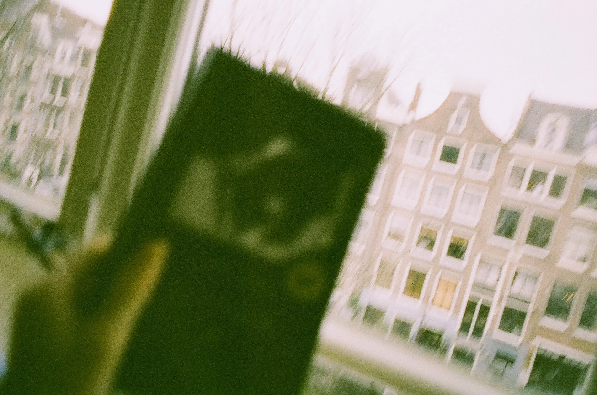 Close-up of a black object, possibly a part of furniture, with a background of a window and wall with a chevron pattern.