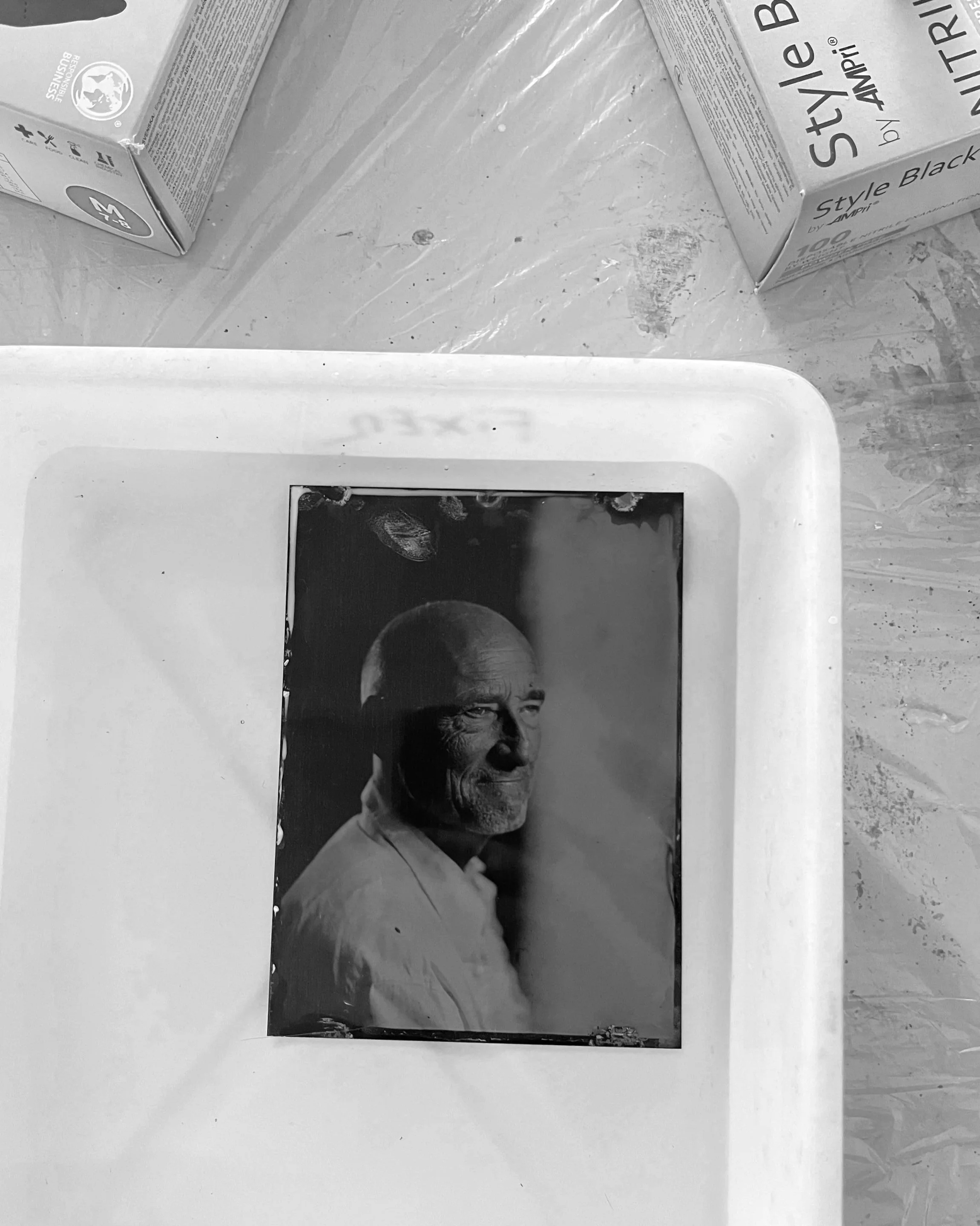 Black and white photograph of a tablet on a table, displaying a portrait of Abraham Lincoln. The tablet is partially covered by a piece of paper or cloth.