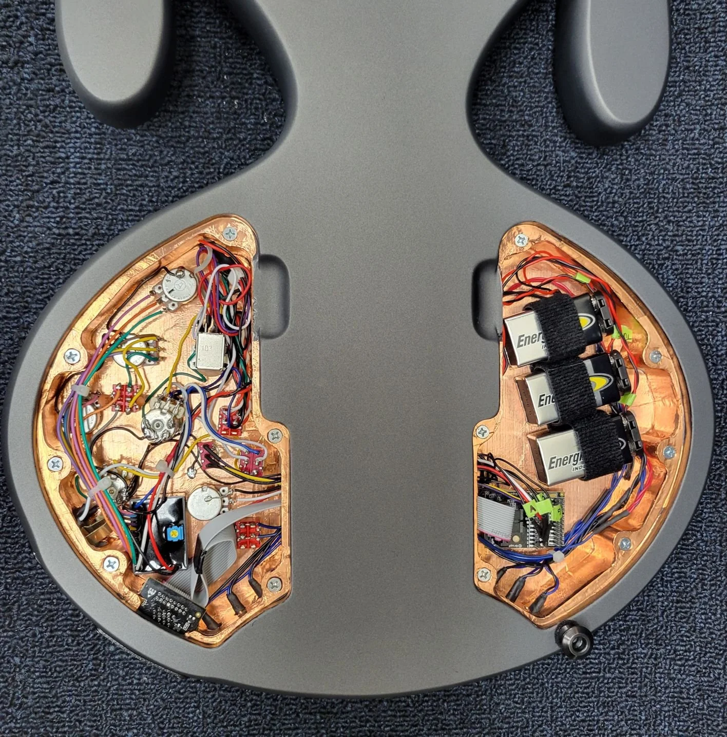 Inside view of a headphone or speaker with circuits, wires, and batteries visible.