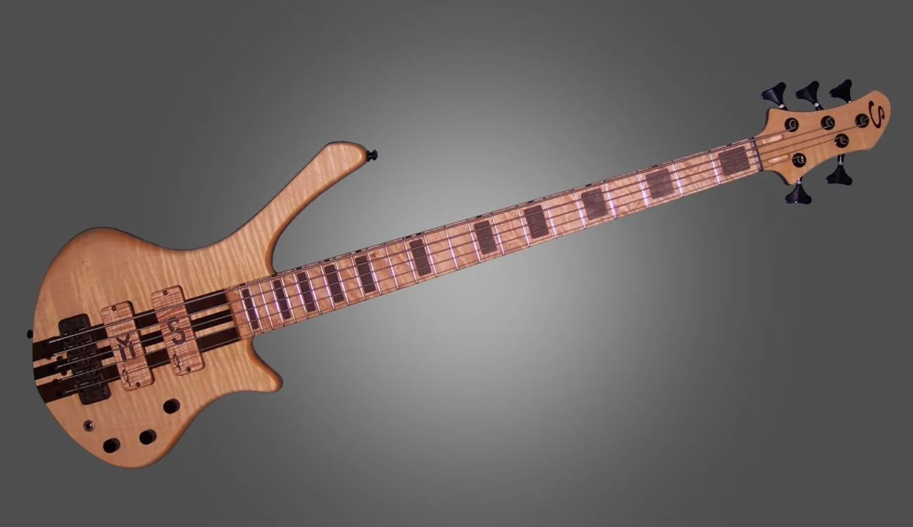 Wooden electric bass guitar with black tuning pegs and fret markers