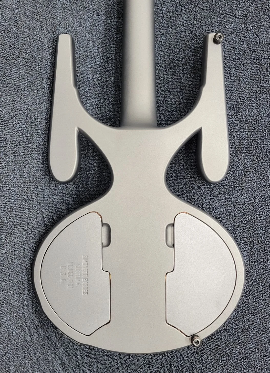 A metal sign holder for a bicycle, possibly for a license plate or registration sticker, lying on a textured gray surface.