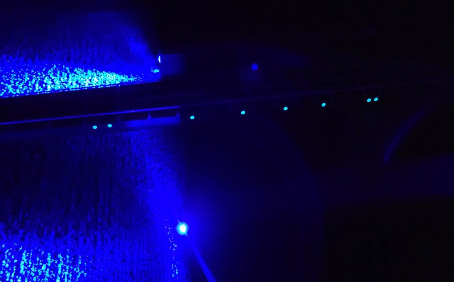 Blue LED lights illuminating a dark ceiling, creating a vibrant glow and pattern on the surface below.