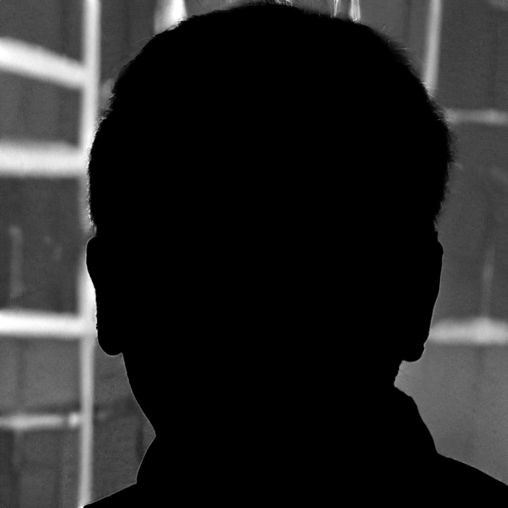 Silhouette of a person's head and shoulders in front of a bright window, with a blurred background of the interior space.