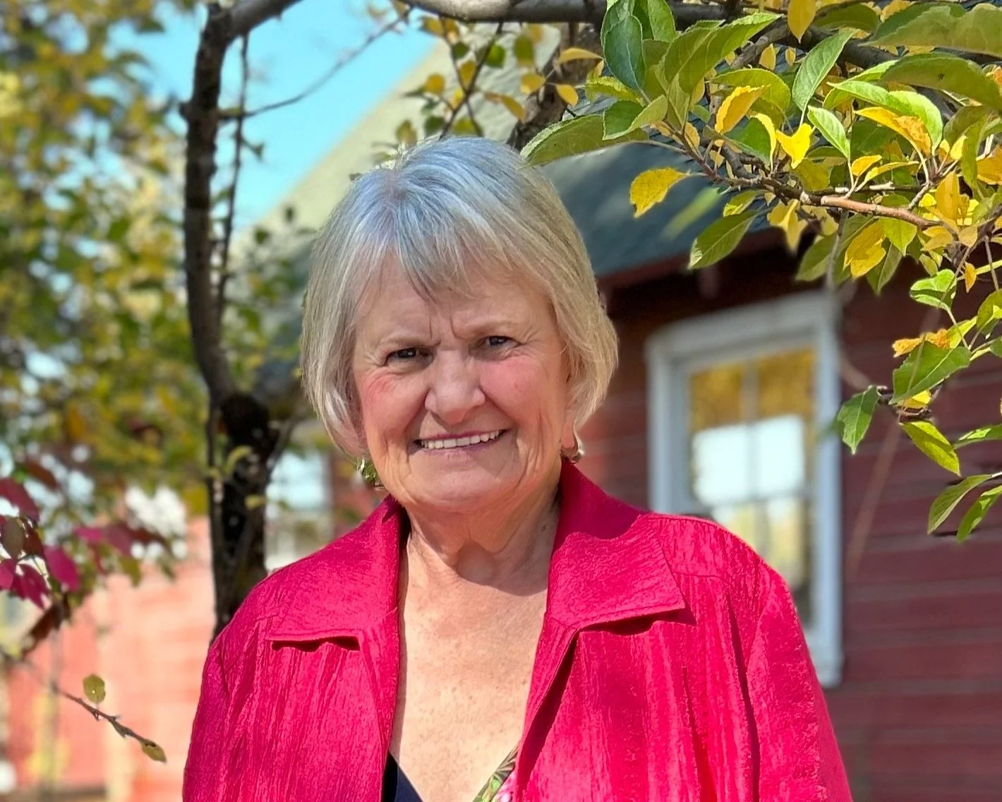 Deanna Gilmore, wearing a bright pink jacket, smiles at the camera.