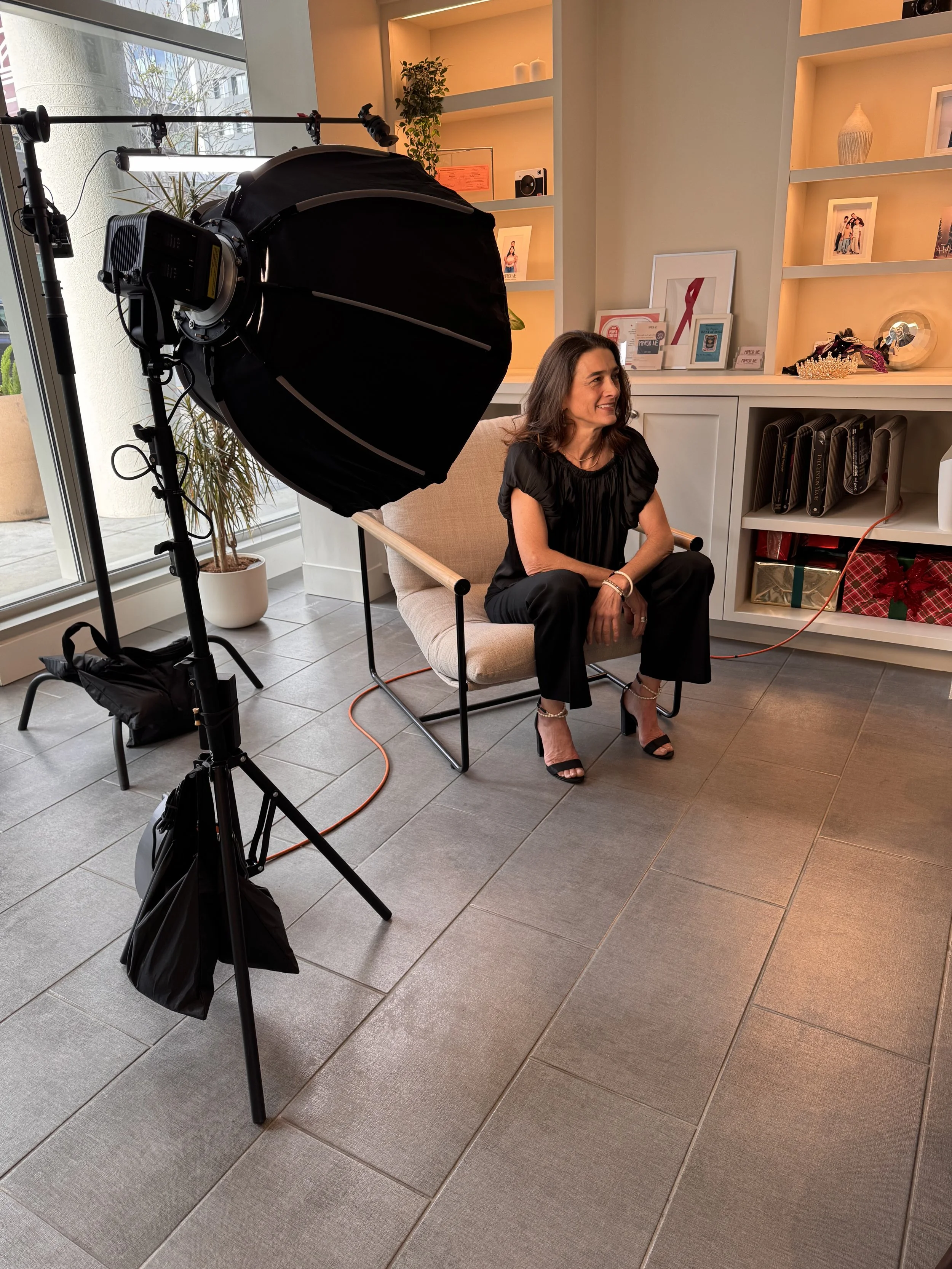 Lisa at photo shoot sitting in chair and smiling while looking away from the camera.