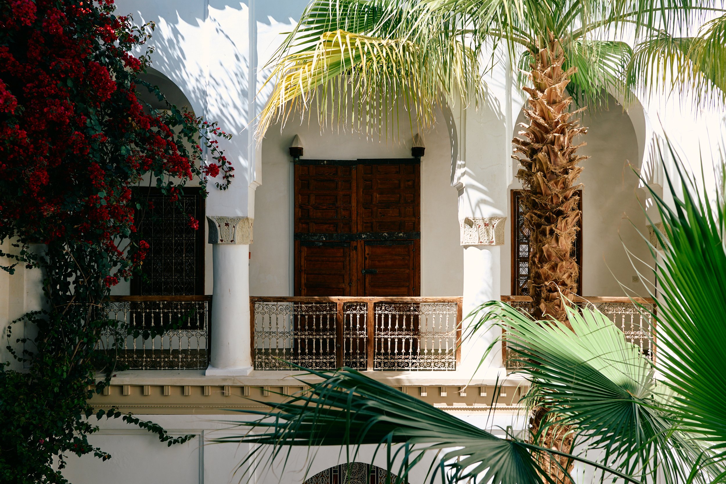 Marokkaanse architectuur in riad Marrakech met witte muren en palmbomen.