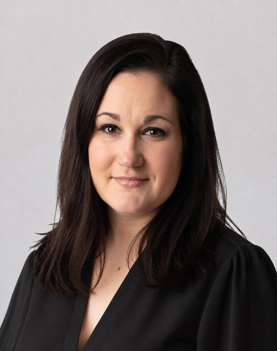 Professional headshot of a woman with shoulder-length dark brown hair, wearing a black blouse against a light gray background.