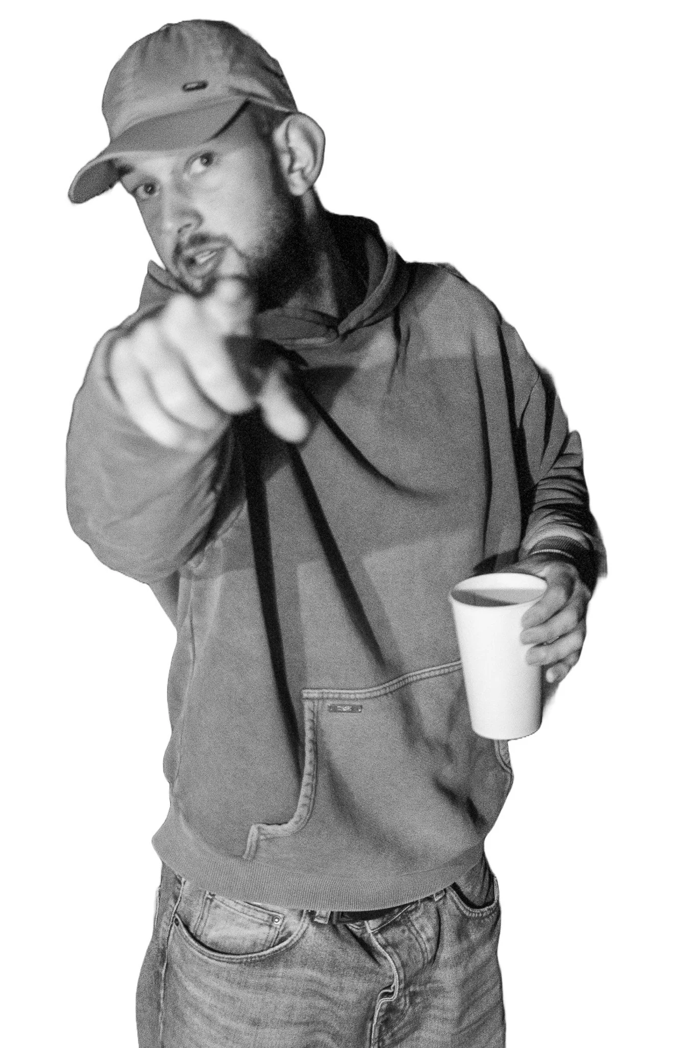 Schwarzweißfoto einer Person mit Kapuze und Baseballkappe, die auf die Kamera zeigt und einen Becher in der anderen Hand hält.