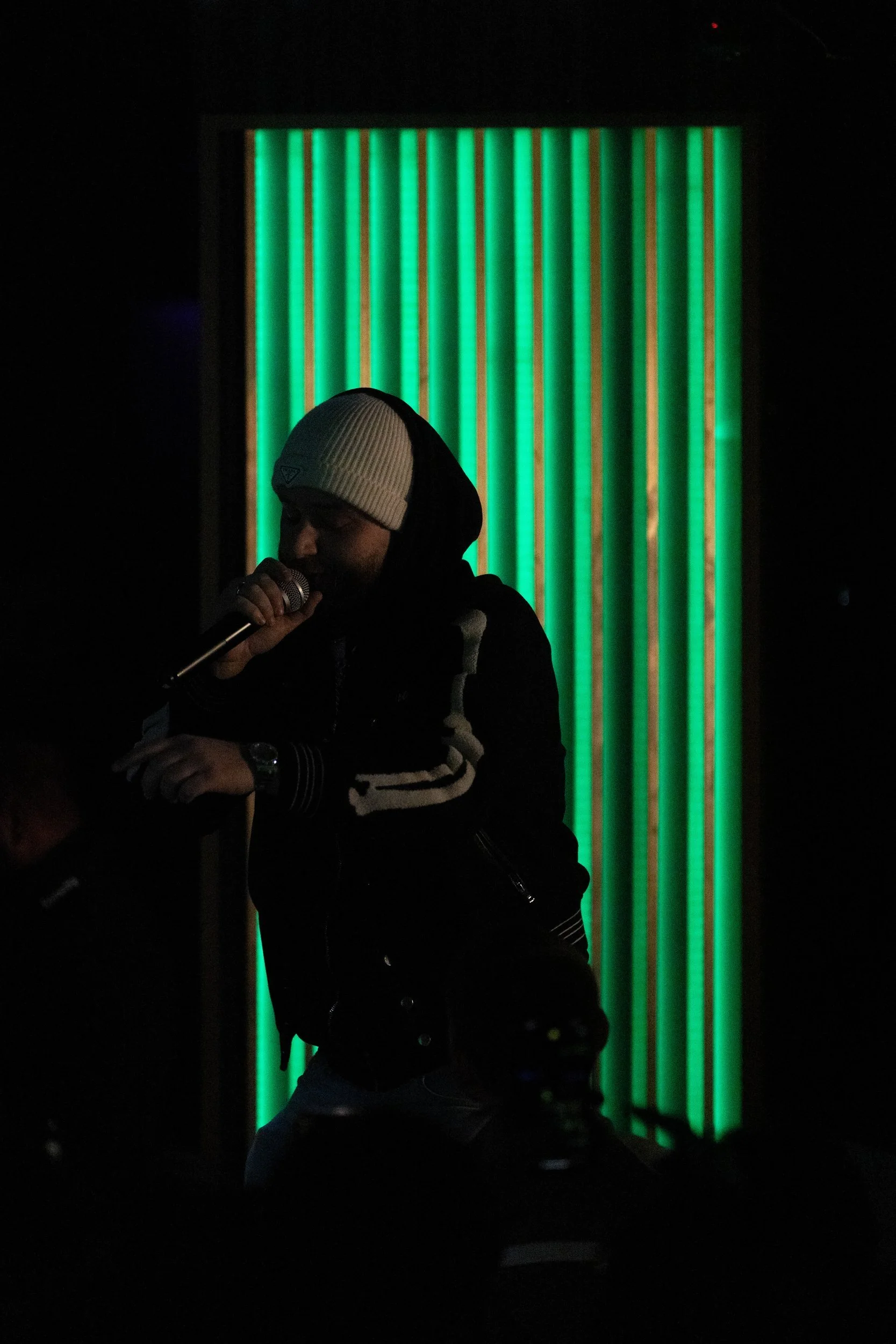Rapper am Mikrofon vor grünem Licht bei der YWL Clubnacht in Berlin
