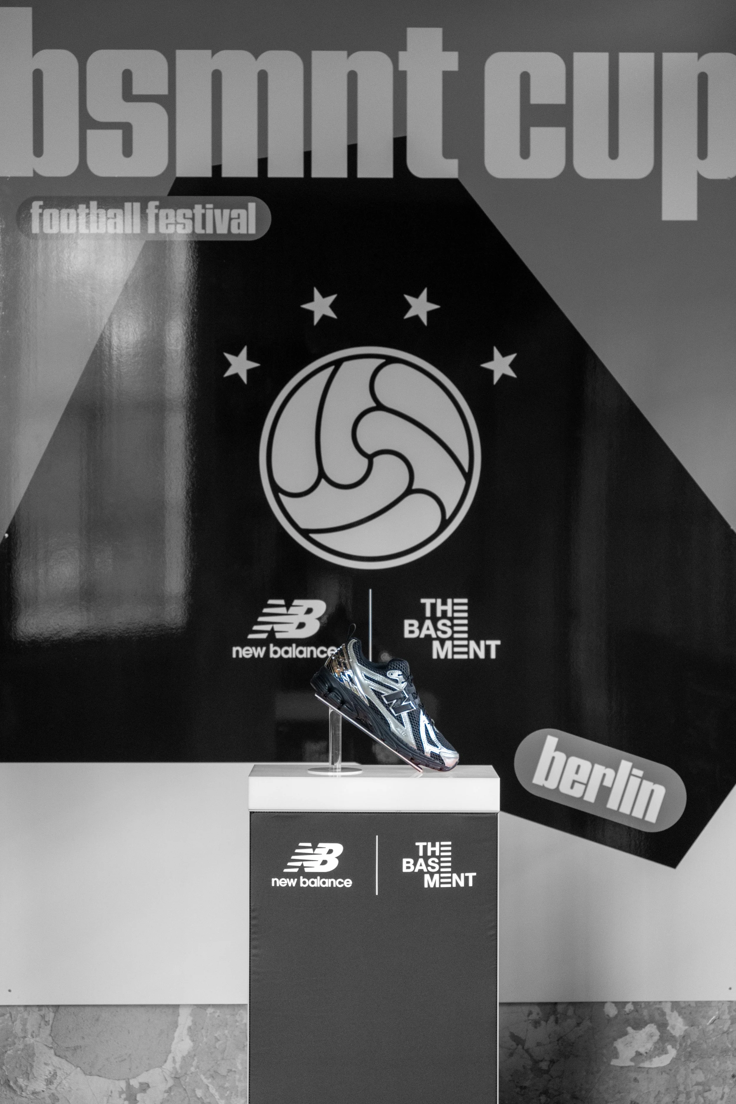 Sneaker auf Podest vor bsmnt cup Poster mit New Balance Logo in Berlin.