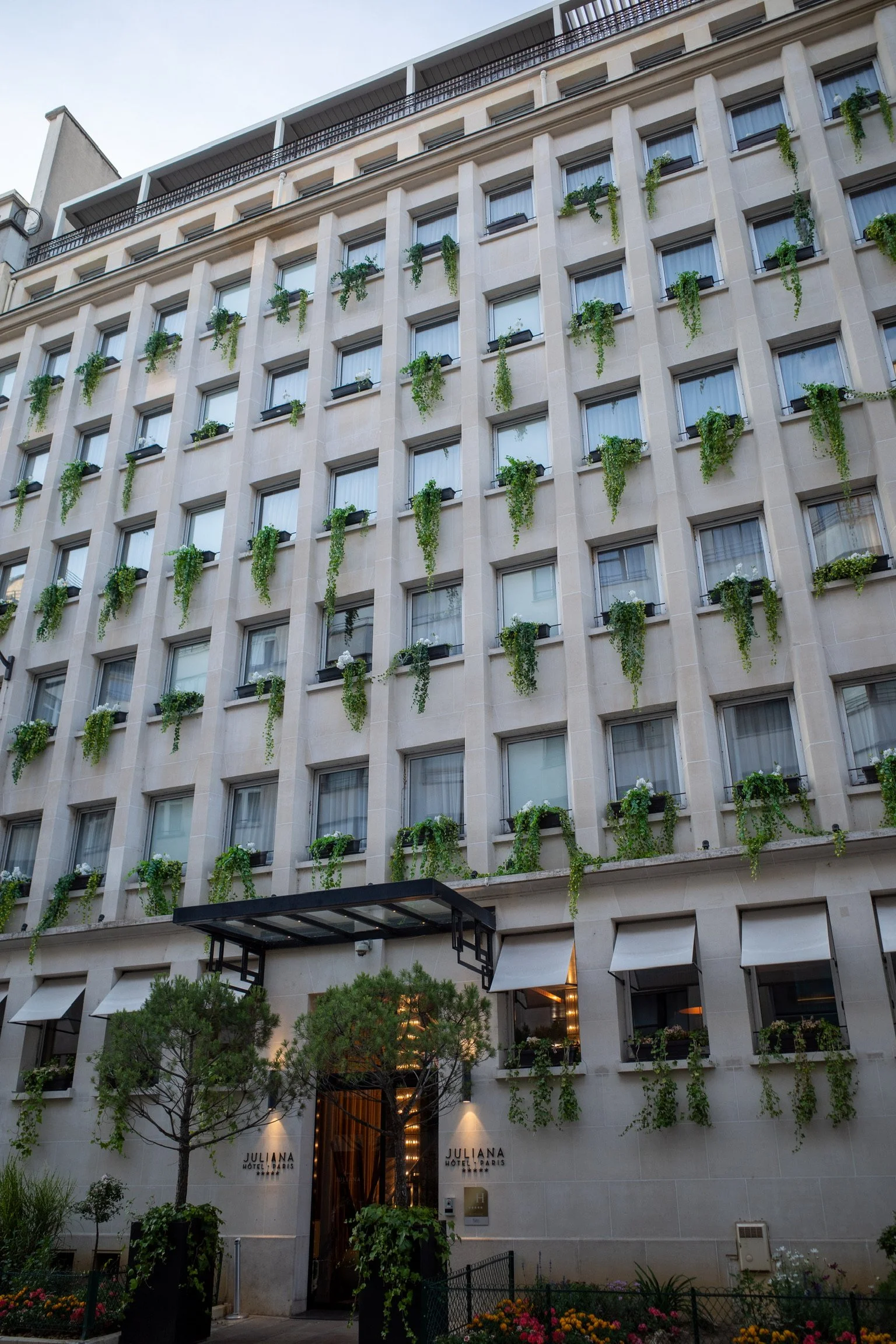 Hotelgebäude mit vertikalen Pflanzen an der Fassade, großen Fenstern und einem Eingang mit Vordach.