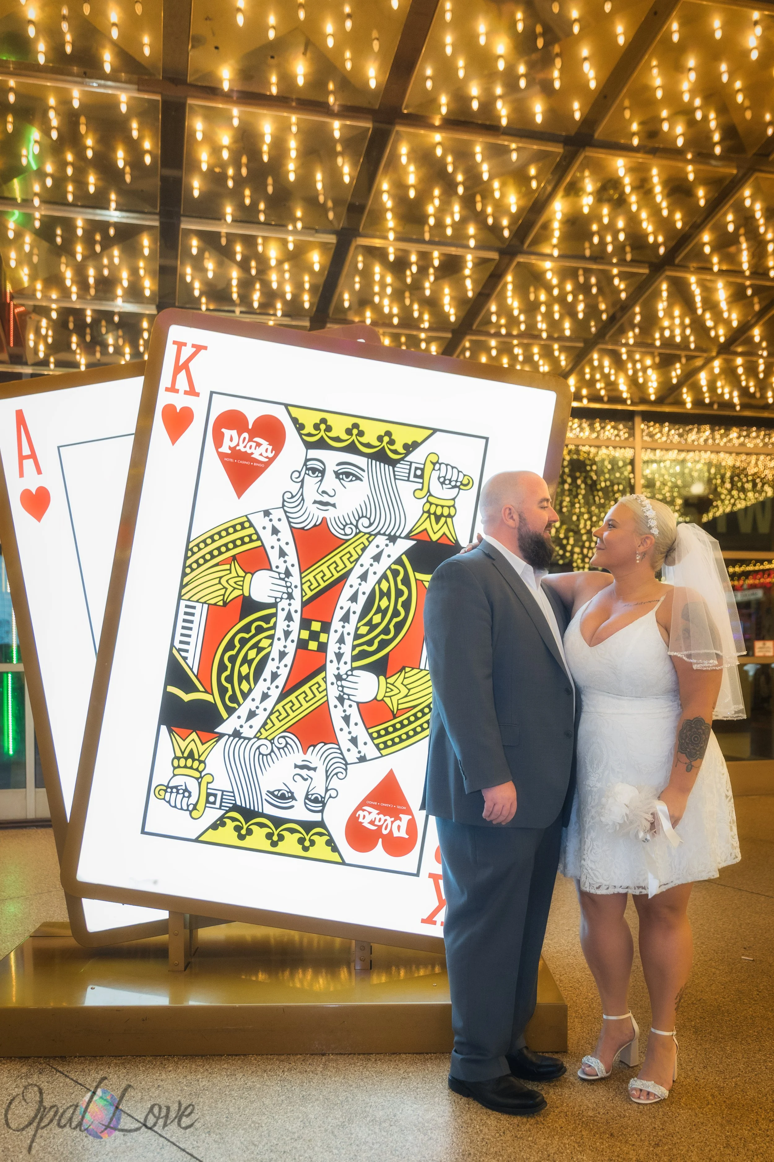 Couple posing together in front of giant King and Ace playing card art at the Plaza.